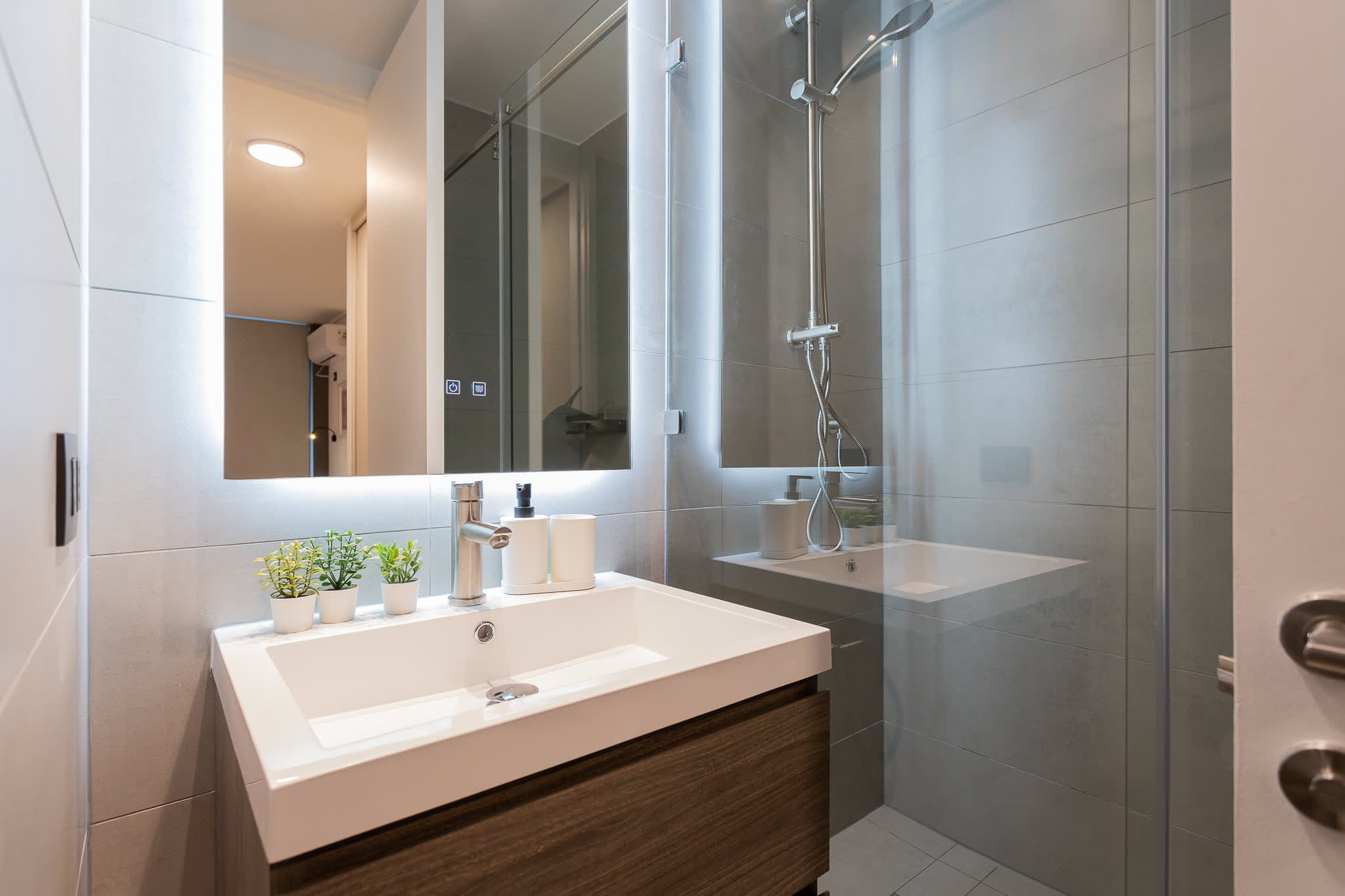 Experience a sleek and modern bathroom with ambient lighting and stylish decor, perfect for a refreshing retreat.
