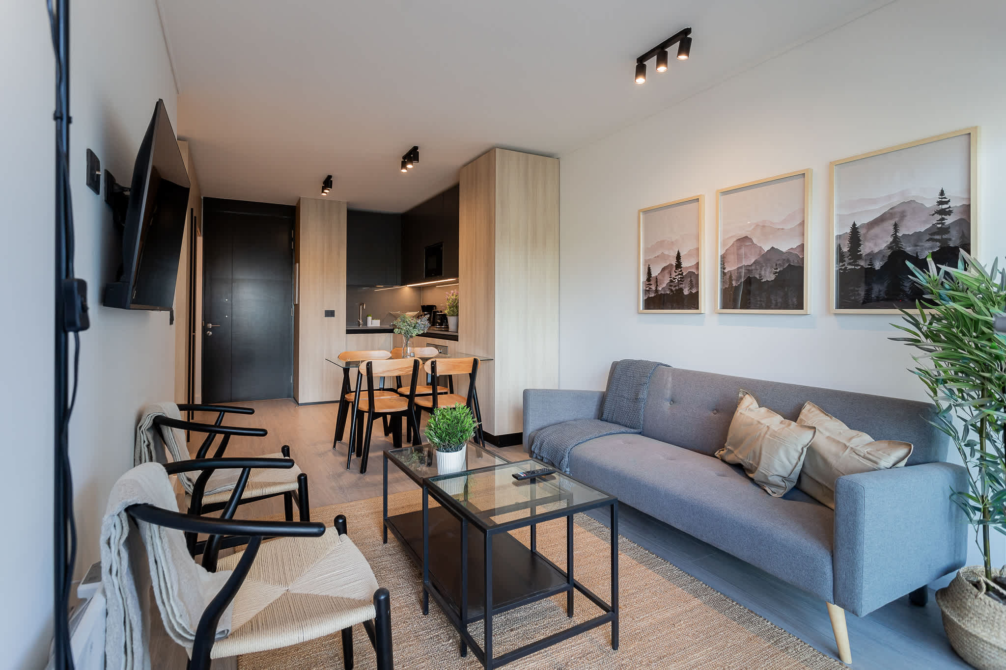 Experience modern comfort in this stylish living space, featuring a cozy sofa, dining area, and beautiful mountain artwork.