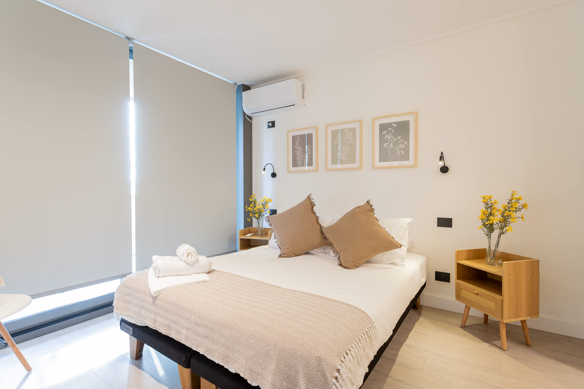 Experience comfort in this stylish bedroom, featuring a cozy queen bed, modern decor, and a touch of nature with fresh flowers.