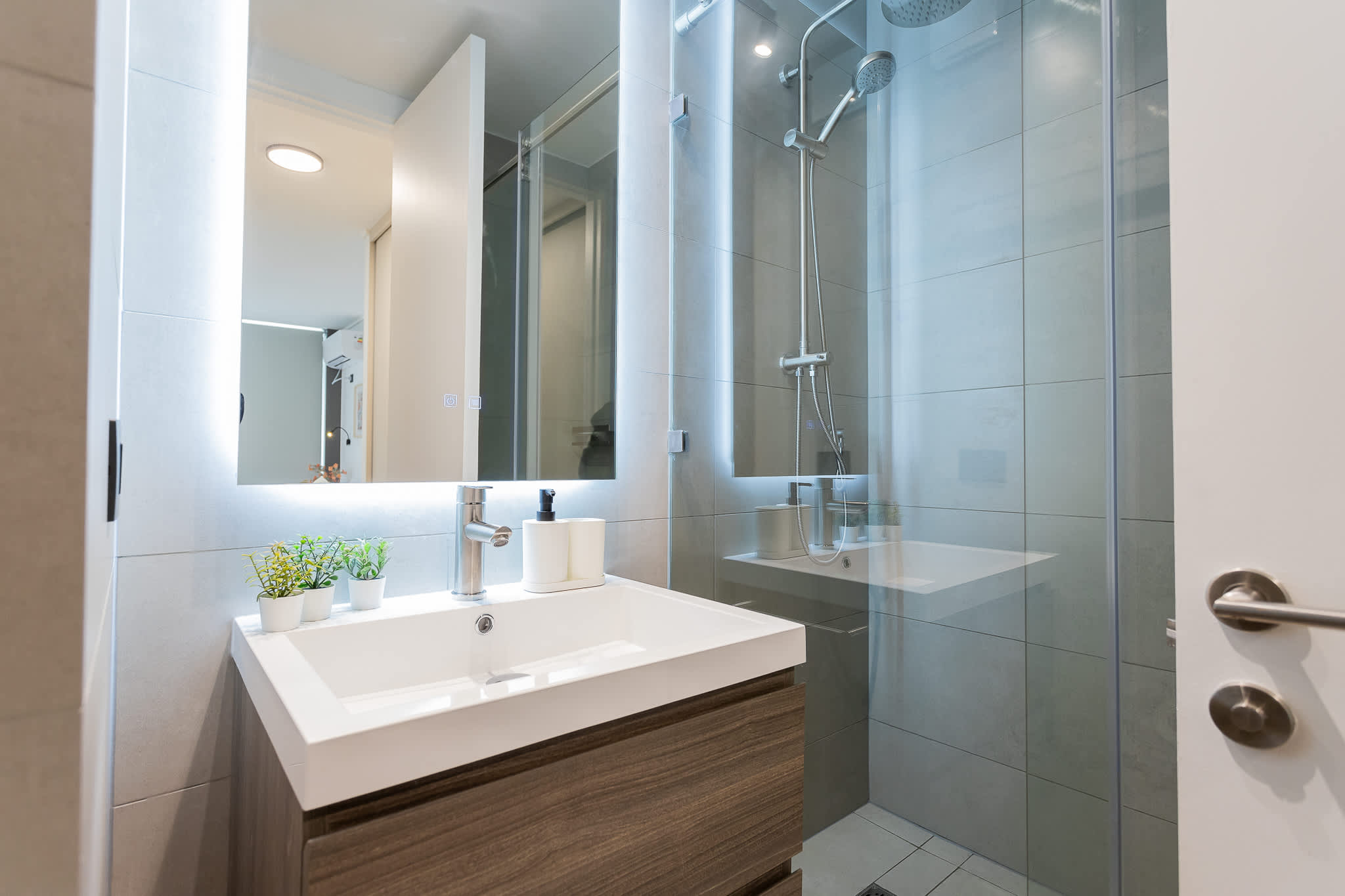 Experience a sleek and modern bathroom with elegant finishes and soothing LED lighting for a refreshing stay.