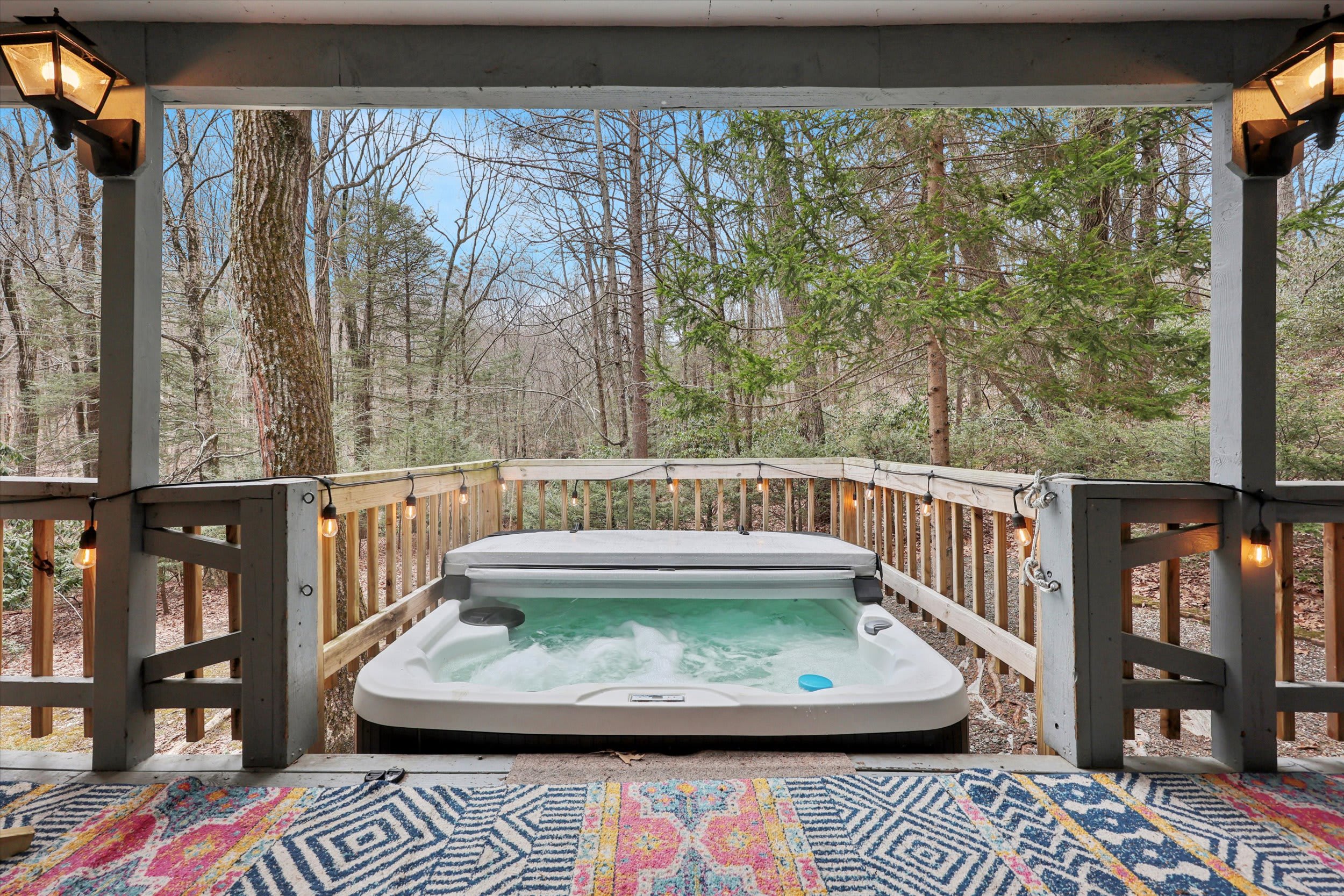 Unwind in the hot tub under string lights on the covered deck after a day of adventure.