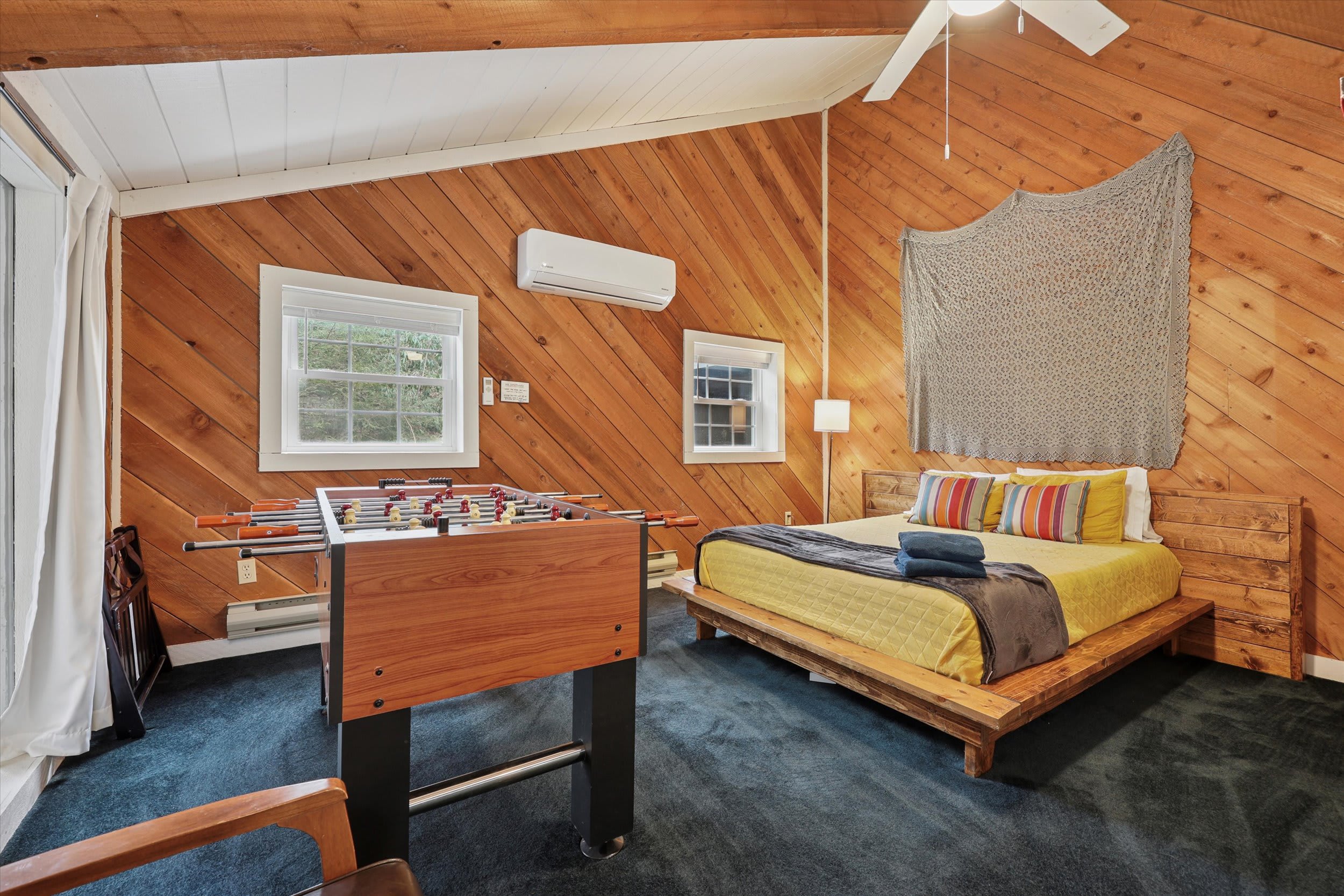 This loft bedroom features a foosball table for rainy-day fun and cozy warm wood paneling.