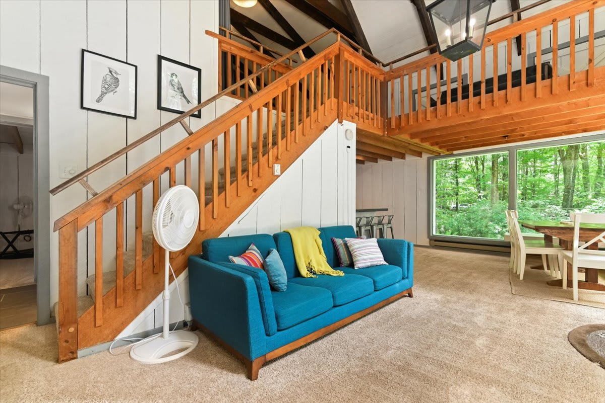 The colorful teal sofa invites you to unwind by the wood stove with the loft above.