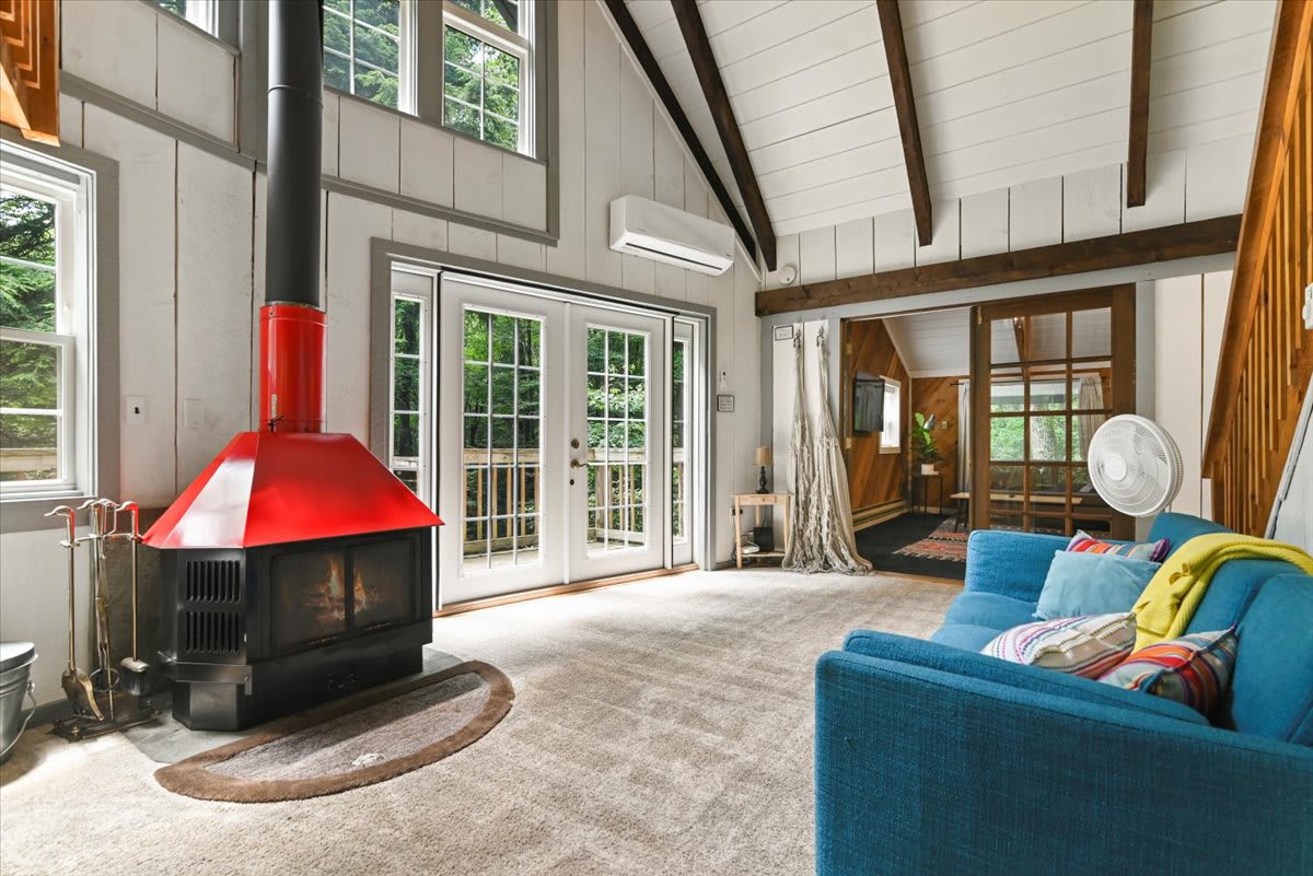 Curl up by the cozy wood-burning fireplace in this bright, vaulted living room with forest views.