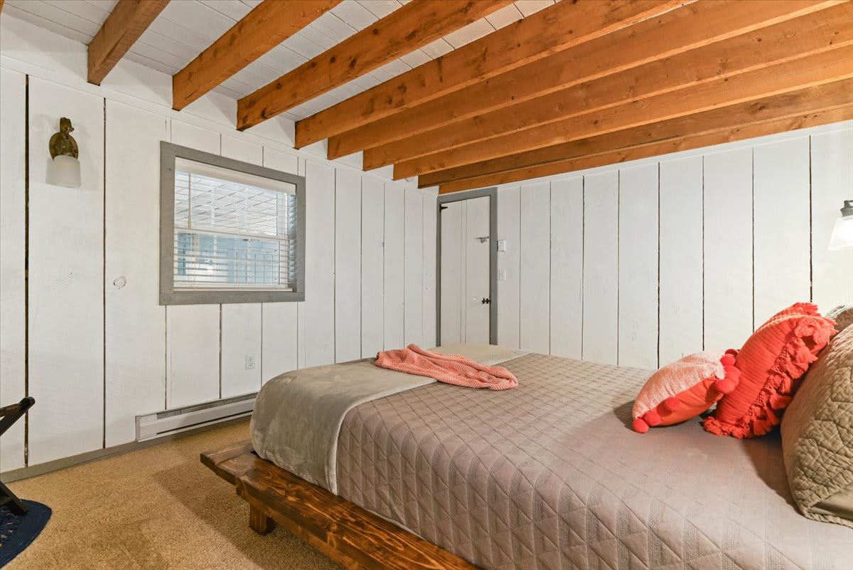 Natural light floods the master bedroom through windows overlooking the forest.