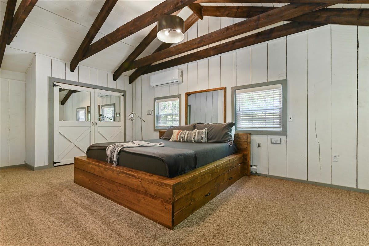 Sleep soundly in the loft bedroom with its rustic wood bed and forest-view windows.
