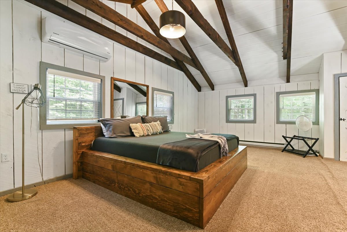 The loft bedroom features mirrored barn doors and soaring beamed ceilings.