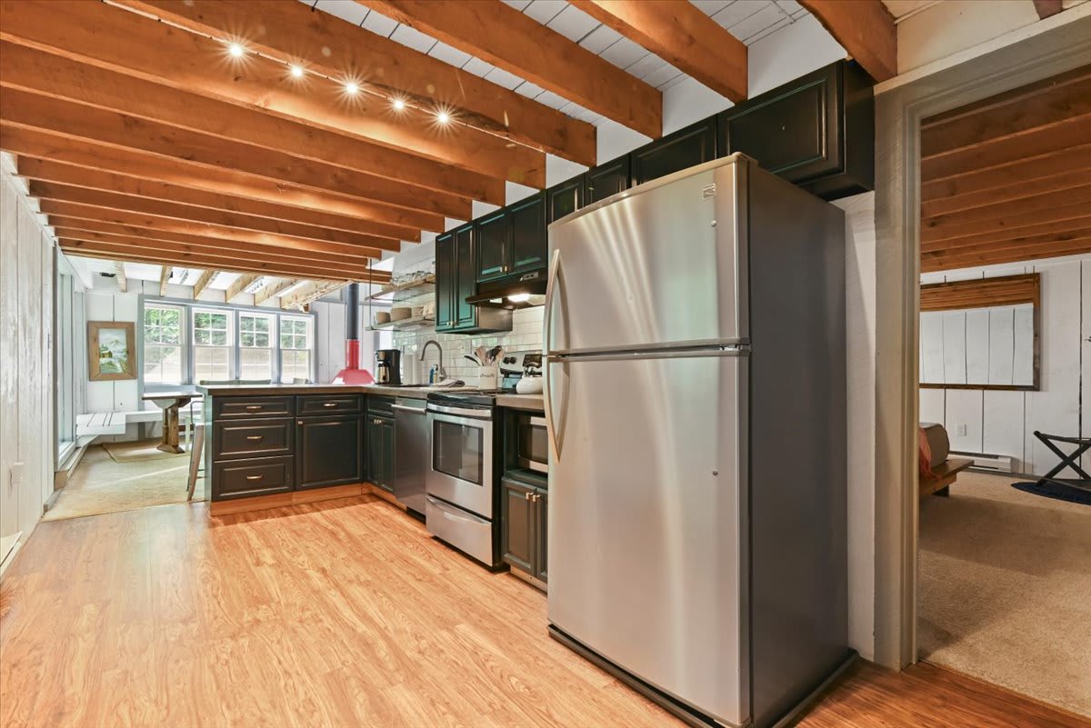 The spacious kitchen offers stainless steel appliances, open shelving, and a view to the bedroom.