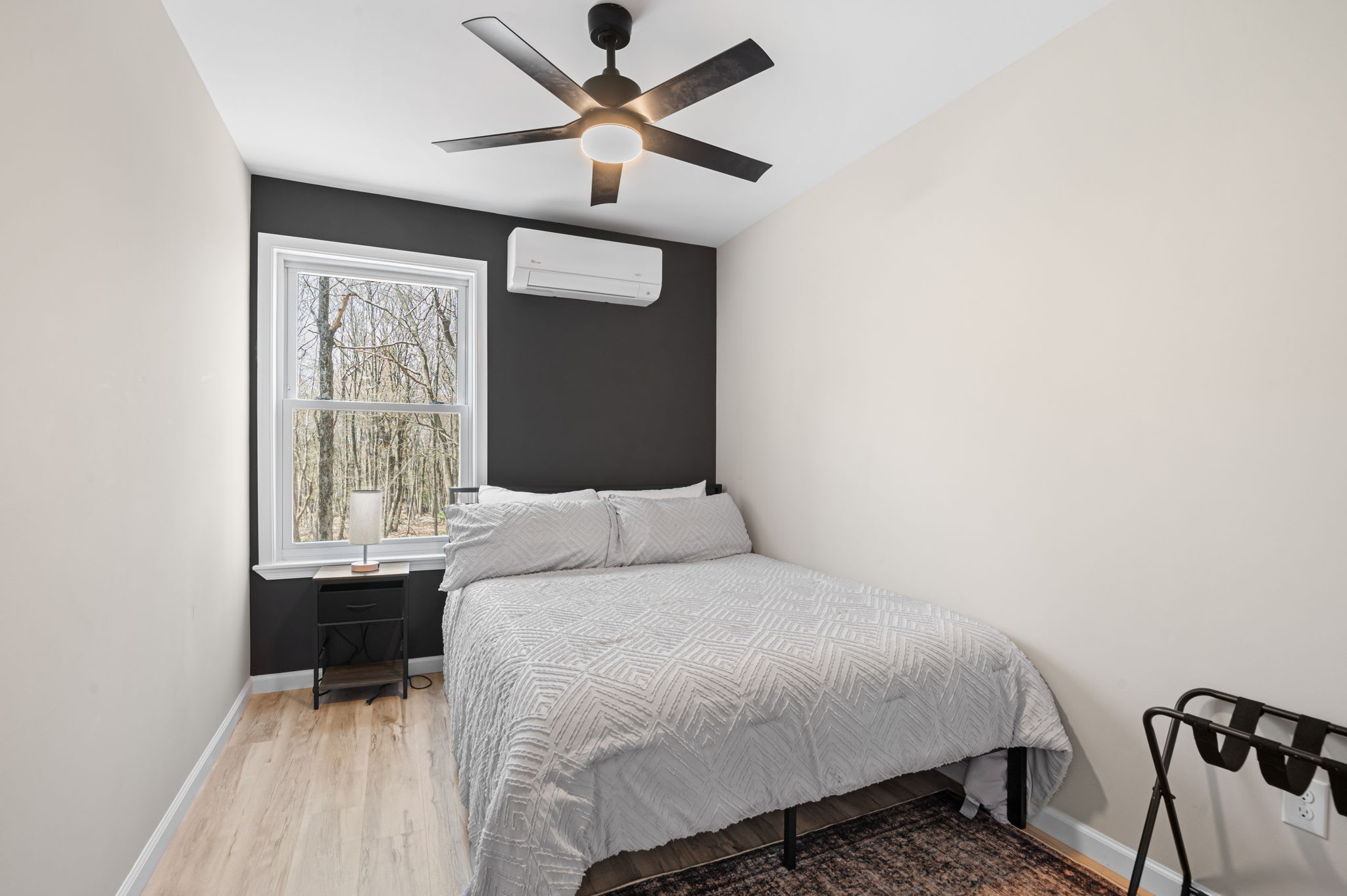 Serene bedroom with large windows offering beautiful wooded views
