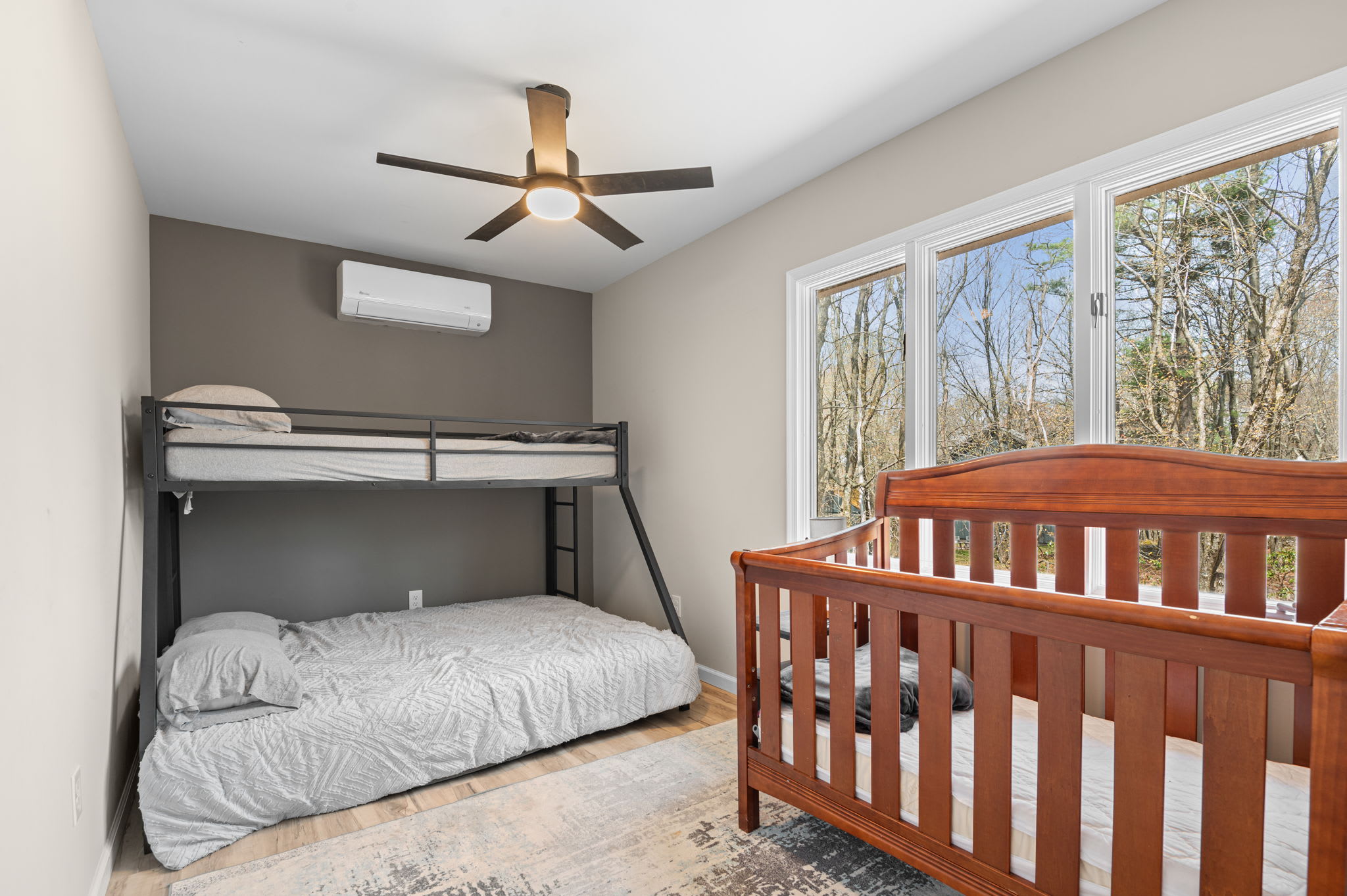 Kids will love this room with a bunk bed, crib, and wooded views