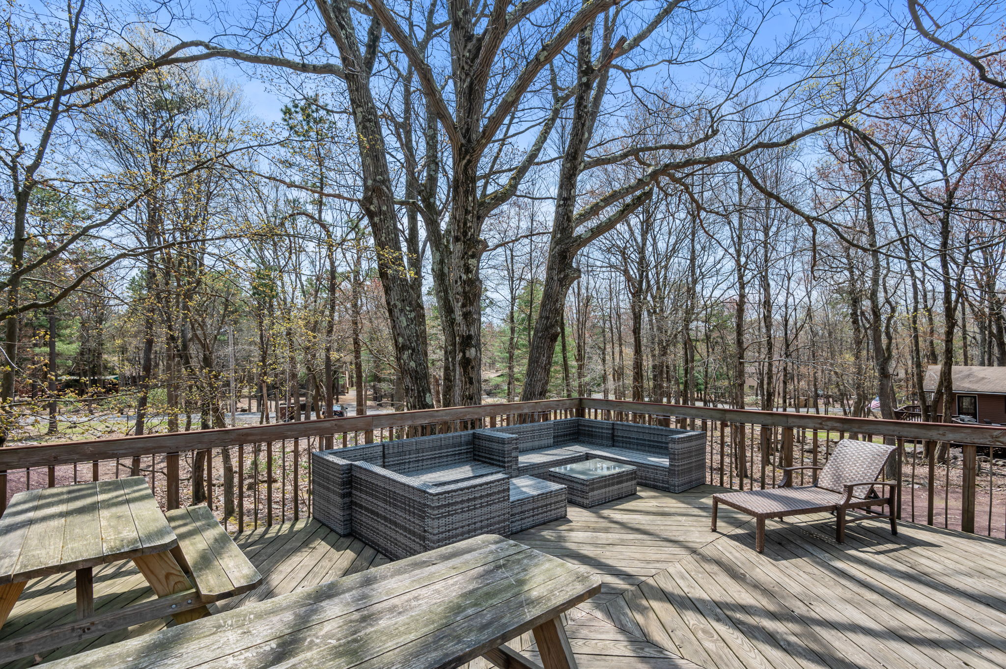 Hot tub and outdoor seating await on this wraparound deck with wooded views