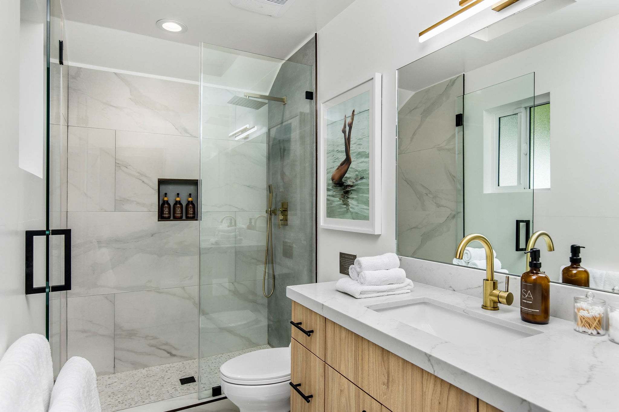 Framed glass, custom vanity, and quiet lighting throughout