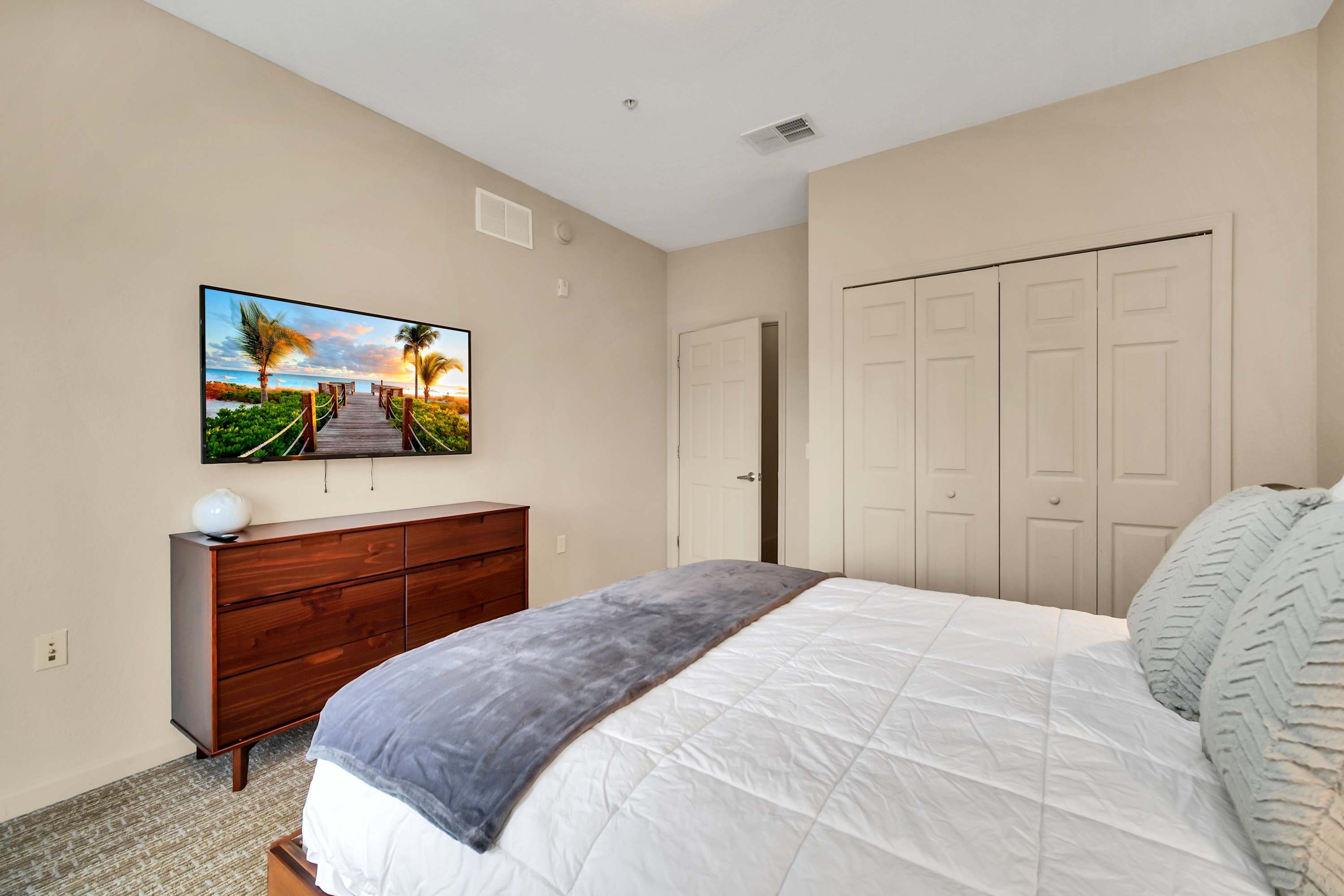 Queen bedroom with stylish decor and smart TV