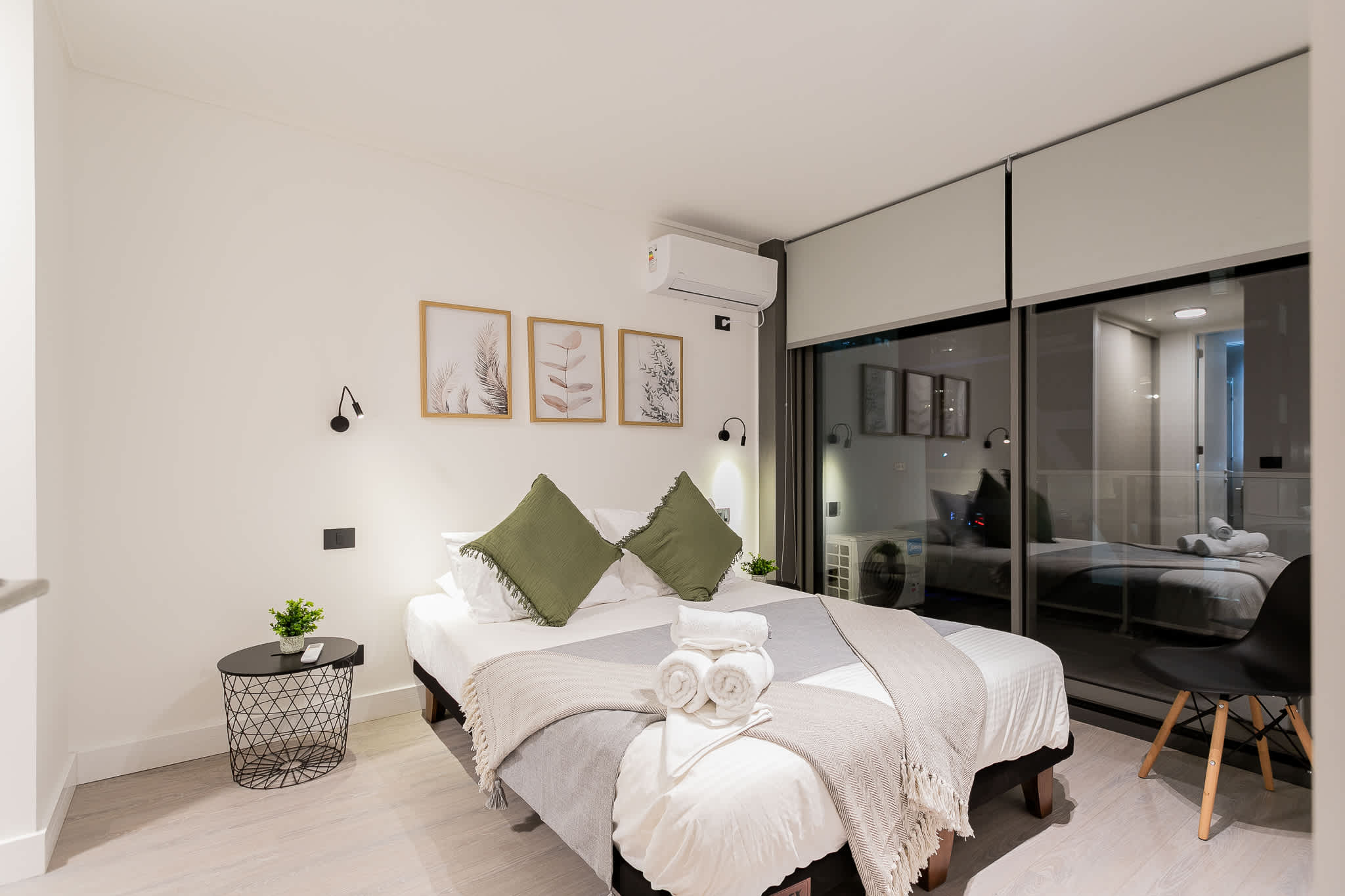 Relax in this stylish bedroom with modern decor, cozy bedding, and a serene view through expansive windows.