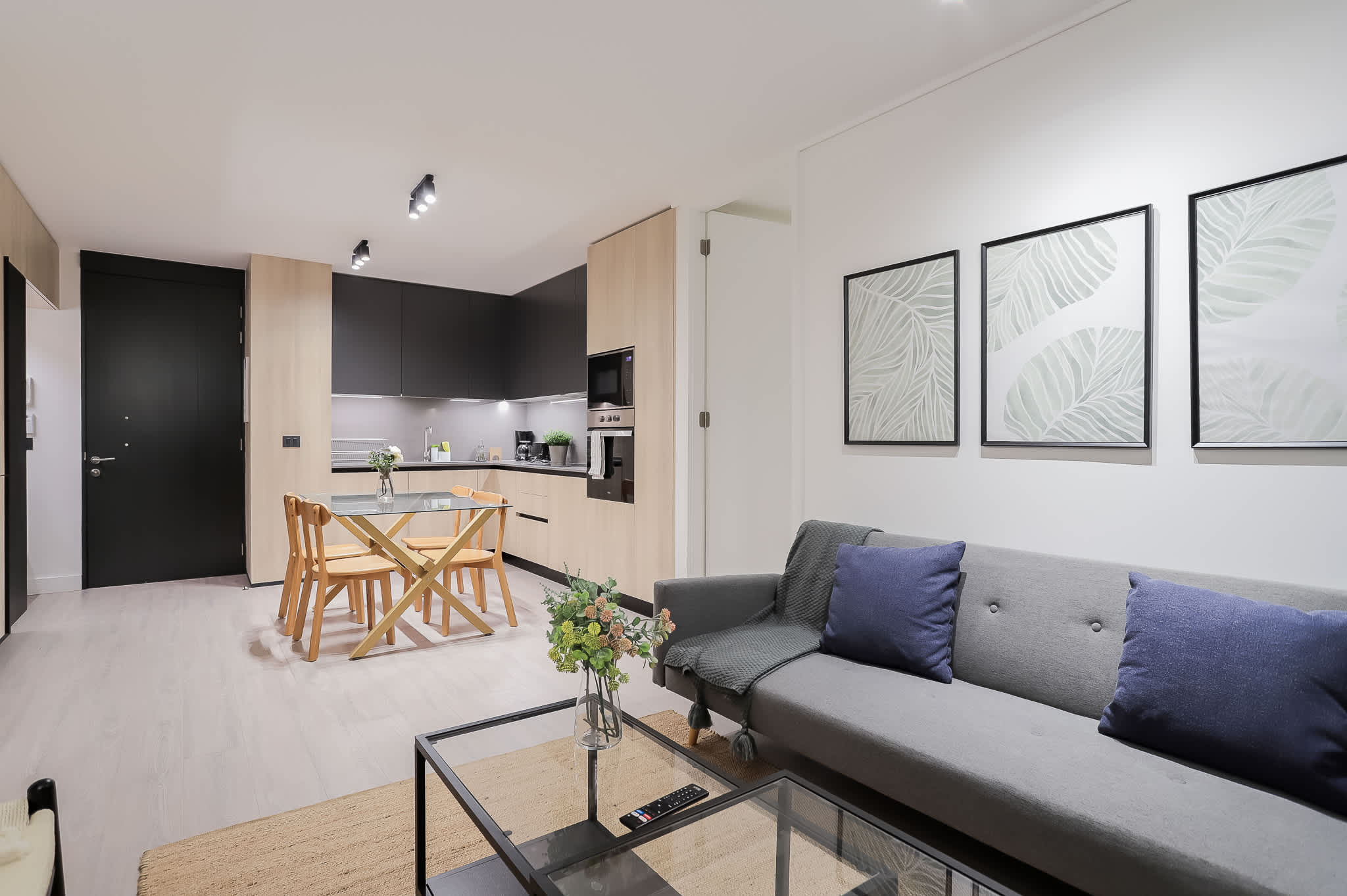Stylish open-plan living area with a cozy sofa and modern kitchen, perfect for relaxing and entertaining.