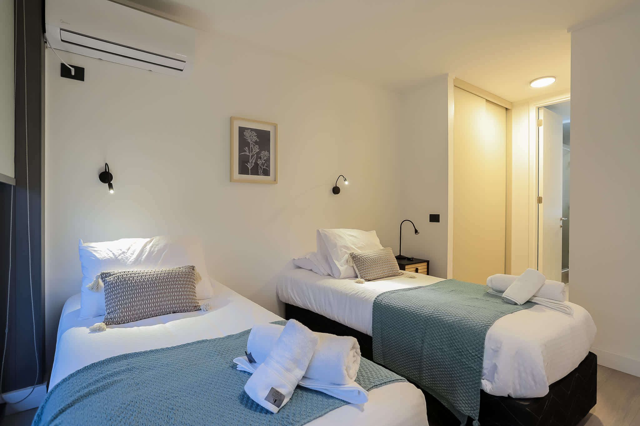 Cozy twin bedroom with modern amenities and stylish decor, perfect for a restful stay.