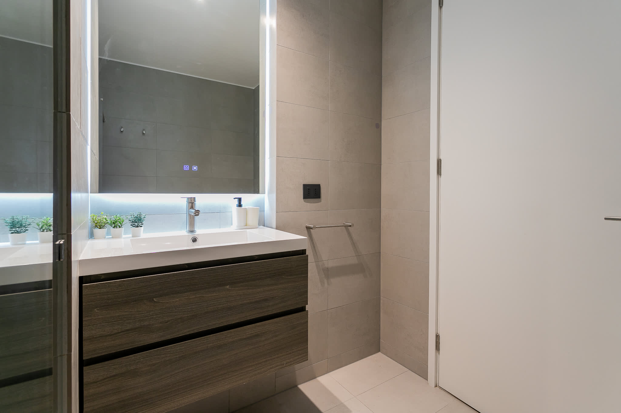 Experience modern elegance in this sleek bathroom, featuring a stylish vanity and ambient lighting for a relaxing retreat.