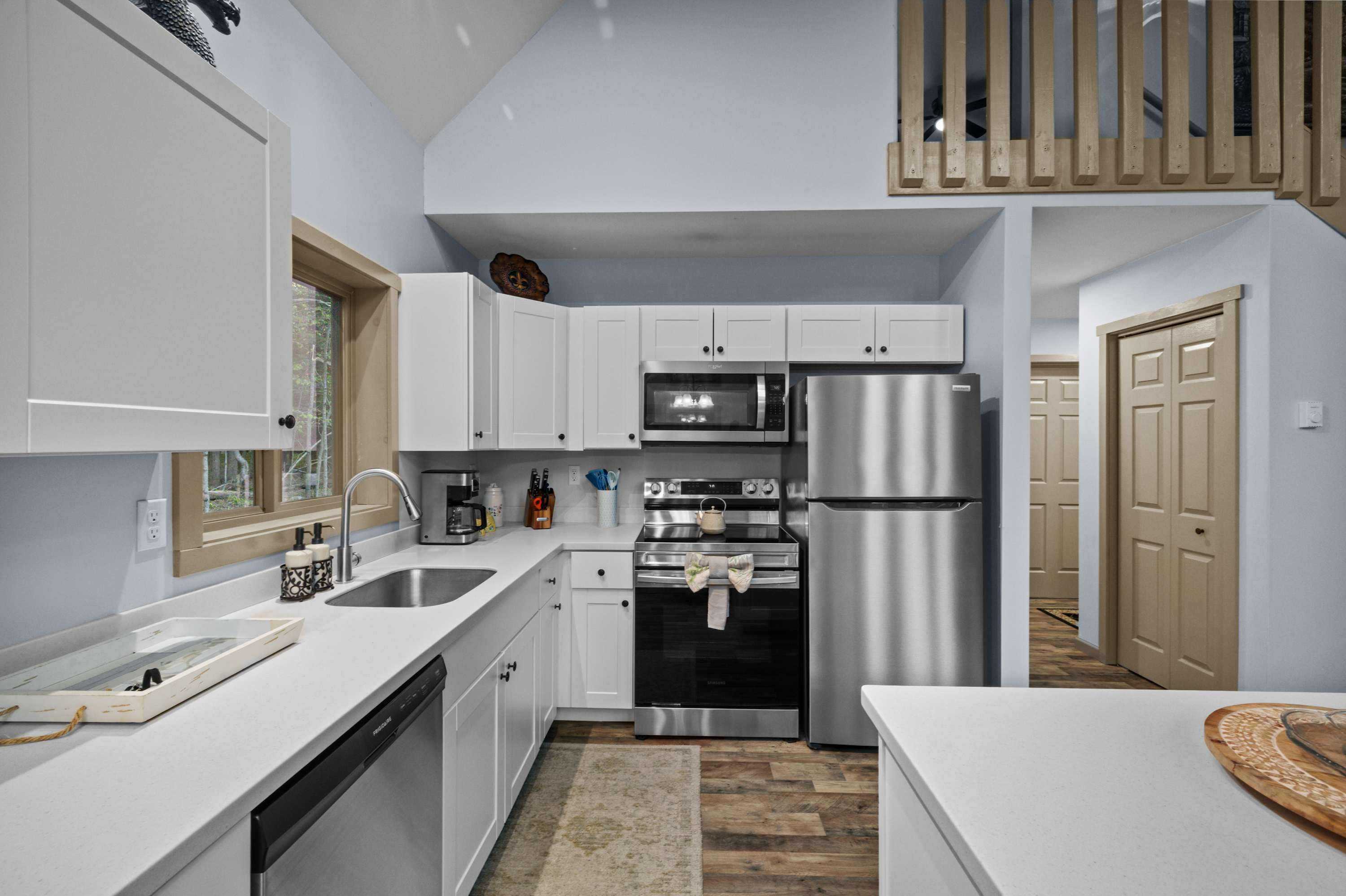 Modern kitchen featuring stainless steel appliances, including a fridge, microwave, electric stove and oven, along with sleek white cabinetry—perfect for whipping up a delicious meal.