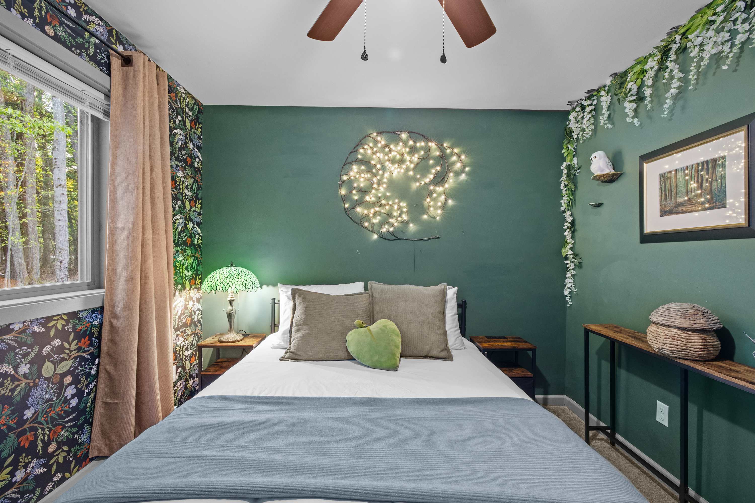 Serene bedroom retreat with a whimsical forest theme. Bedroom #2 features a queen bed, bedside lamp, TV and ceiling fan.