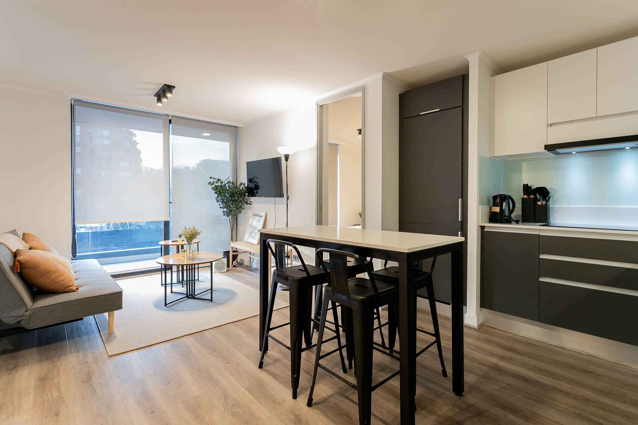 Stylish open-plan living area with modern kitchen, cozy seating, and abundant natural light—perfect for relaxing or entertaining.