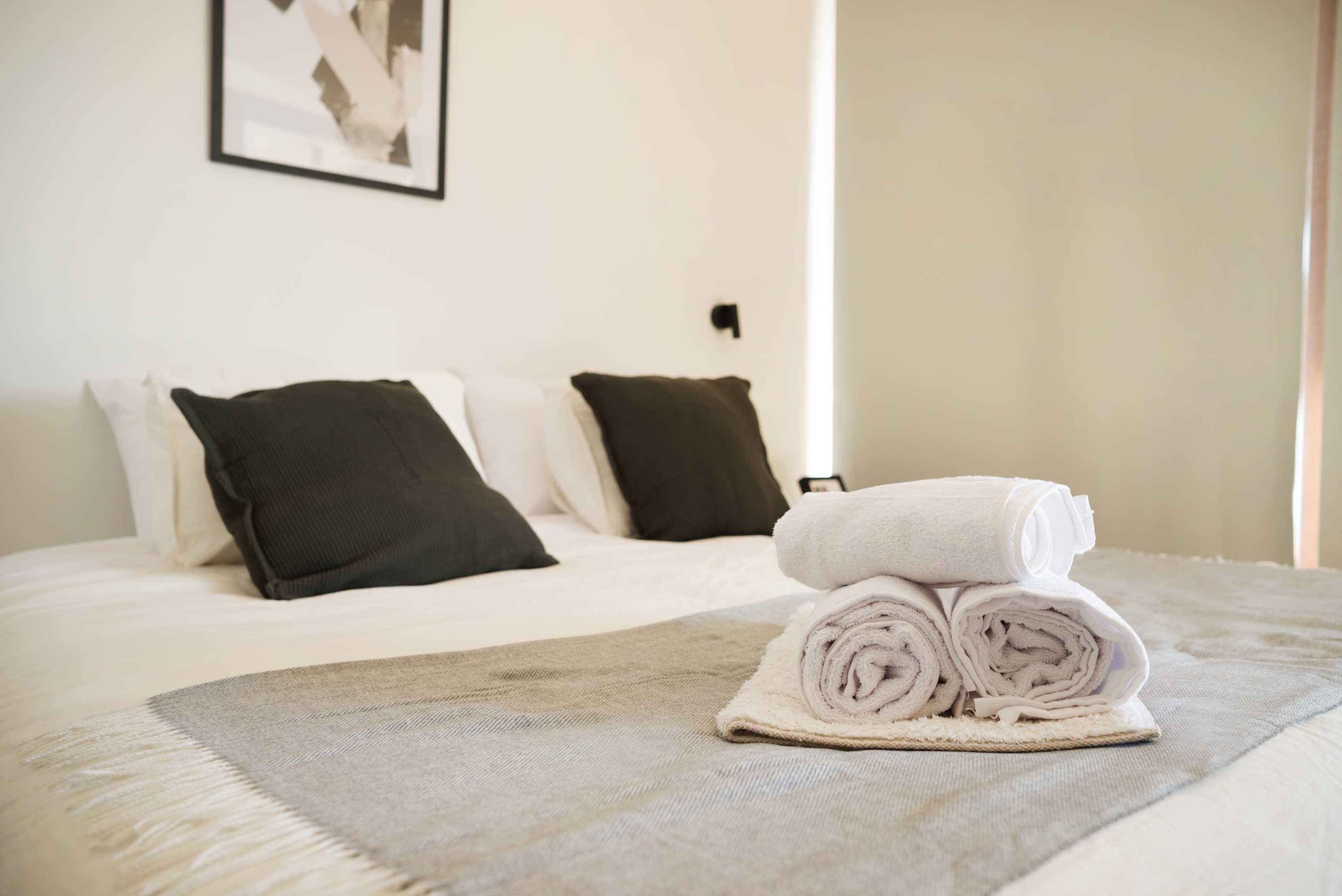 Relax in this cozy bedroom with plush bedding and modern decor, perfect for a restful night's sleep.