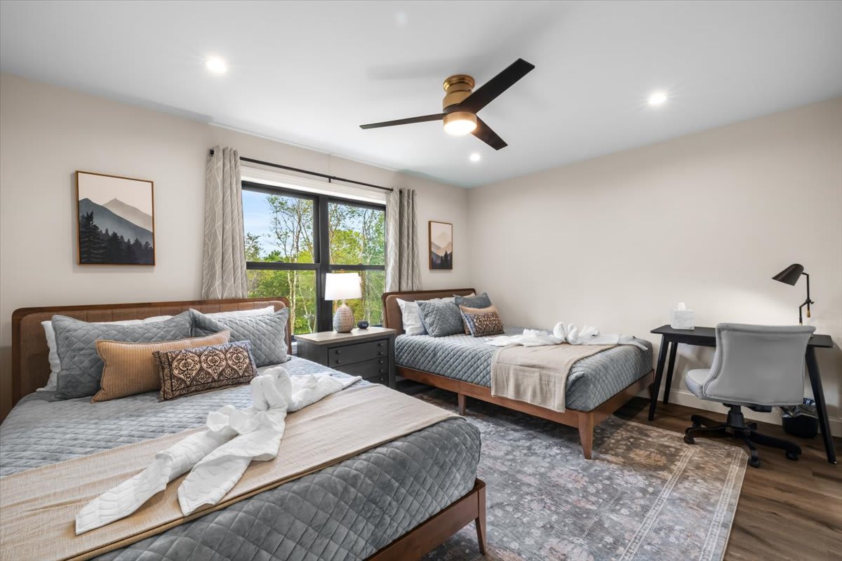 Rest easy under the ceiling fan with scenic artwork and natural light filling this two-queen bedroom.