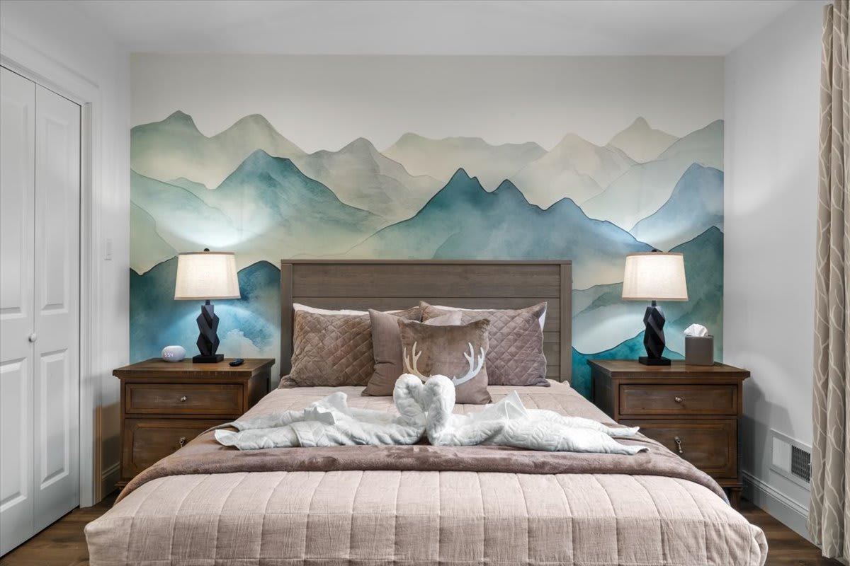 The serene mountain mural creates a tranquil backdrop for restful nights in this cozy bedroom.