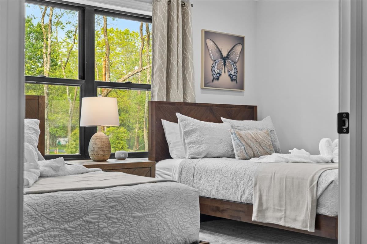 The spacious primary bedroom welcomes guests with two queen beds and serene natural light.