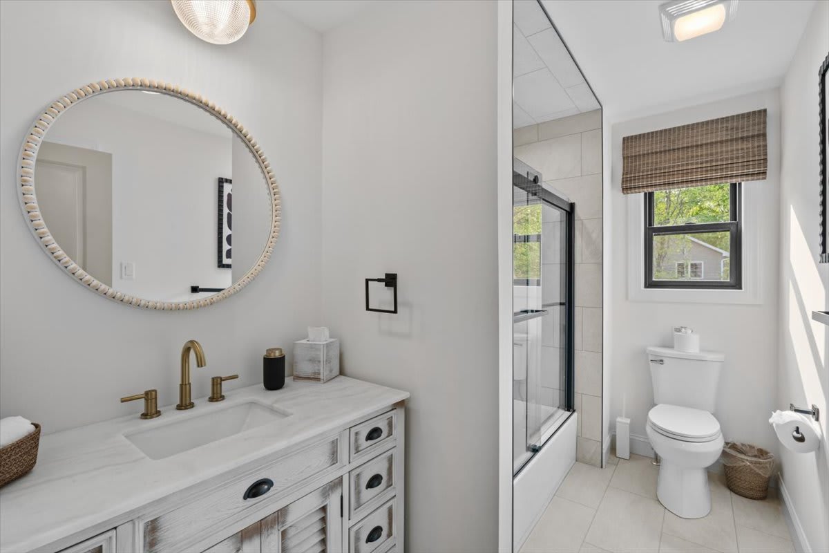 The vintage-style vanity adds charm to this bright bathroom with tub and shower.