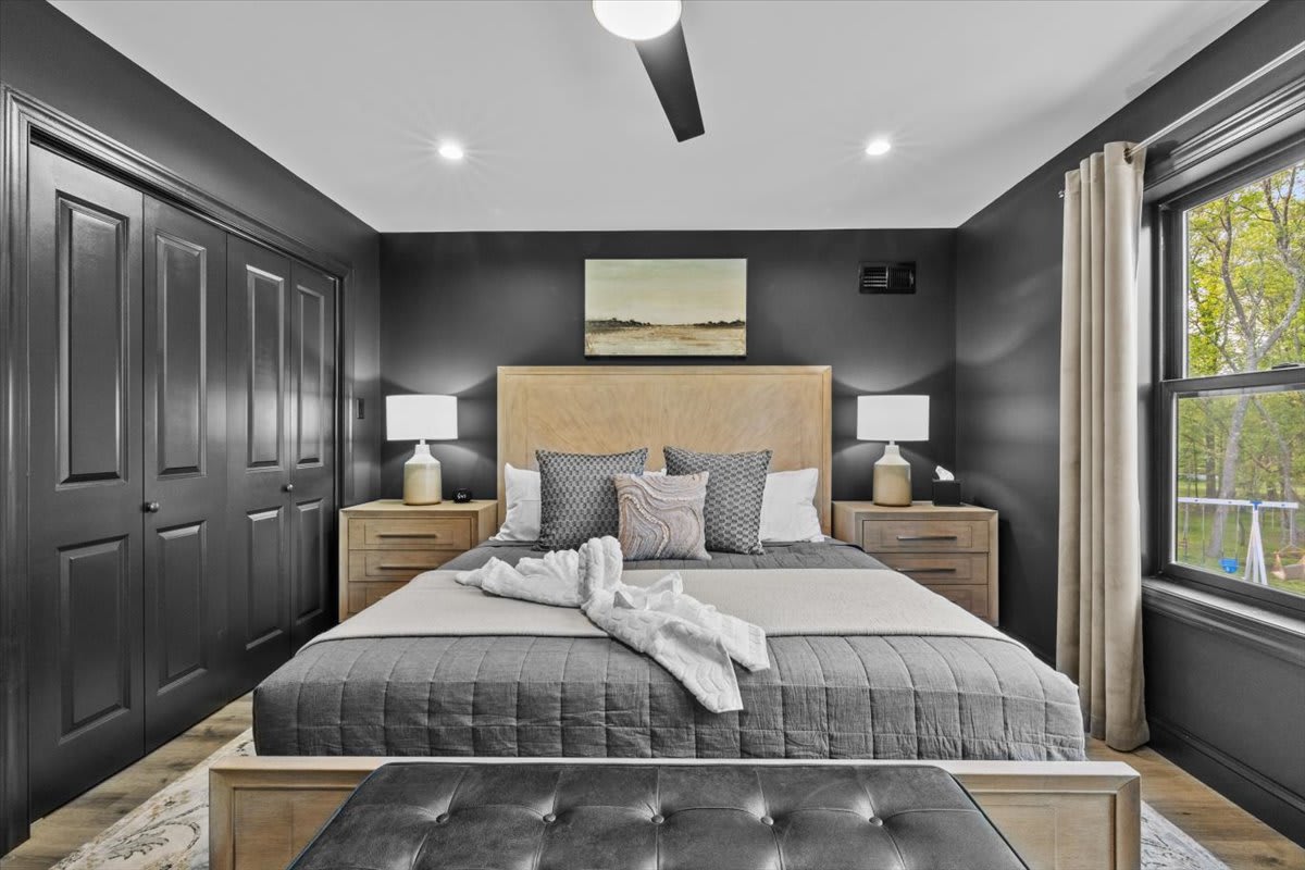 Natural light fills the third bedroom through large windows overlooking the trees.