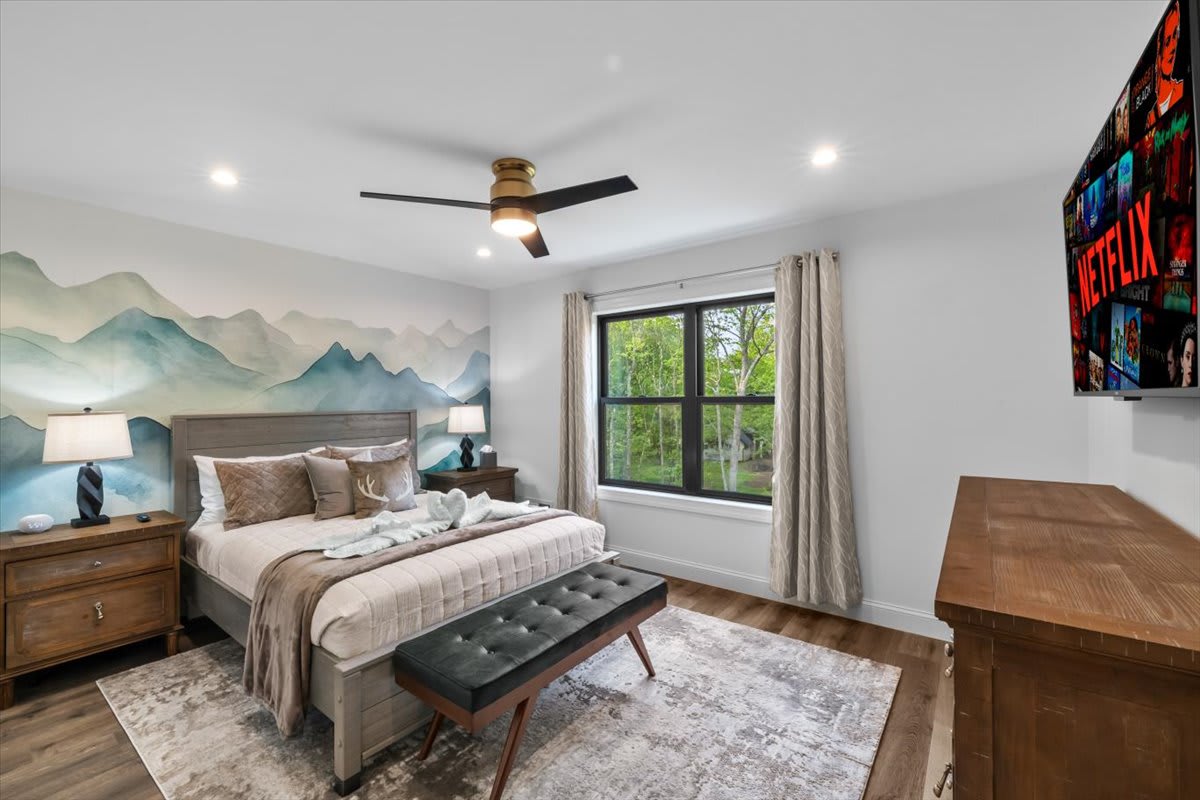 Drift off beneath the artistic headboard in this cozy queen bedroom with modern ceiling fan.