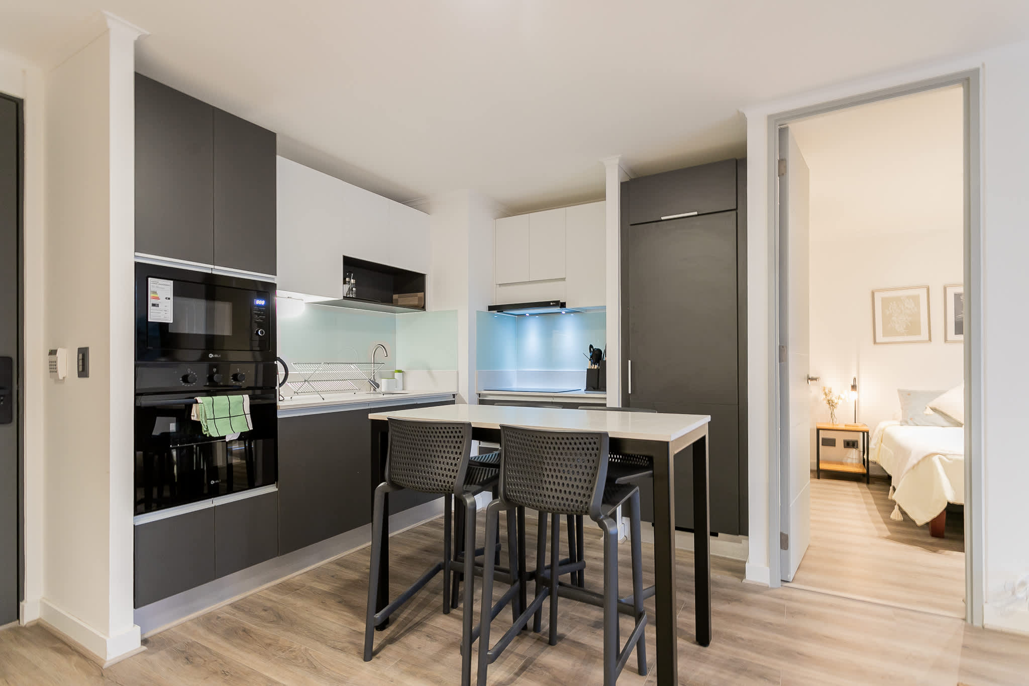 Sleek and modern kitchen with integrated appliances and cozy dining area, perfect for intimate meals.