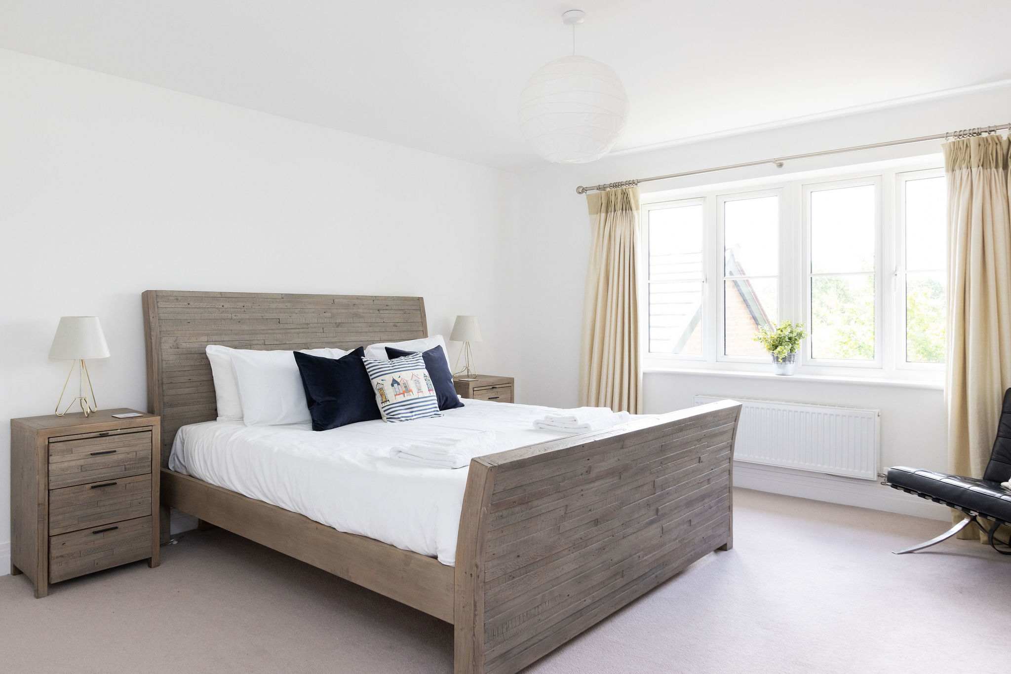 Welcome to the spacious master bedroom, a bright and serene retreat featuring a comfortable king-size bed and stylish wooden furniture.