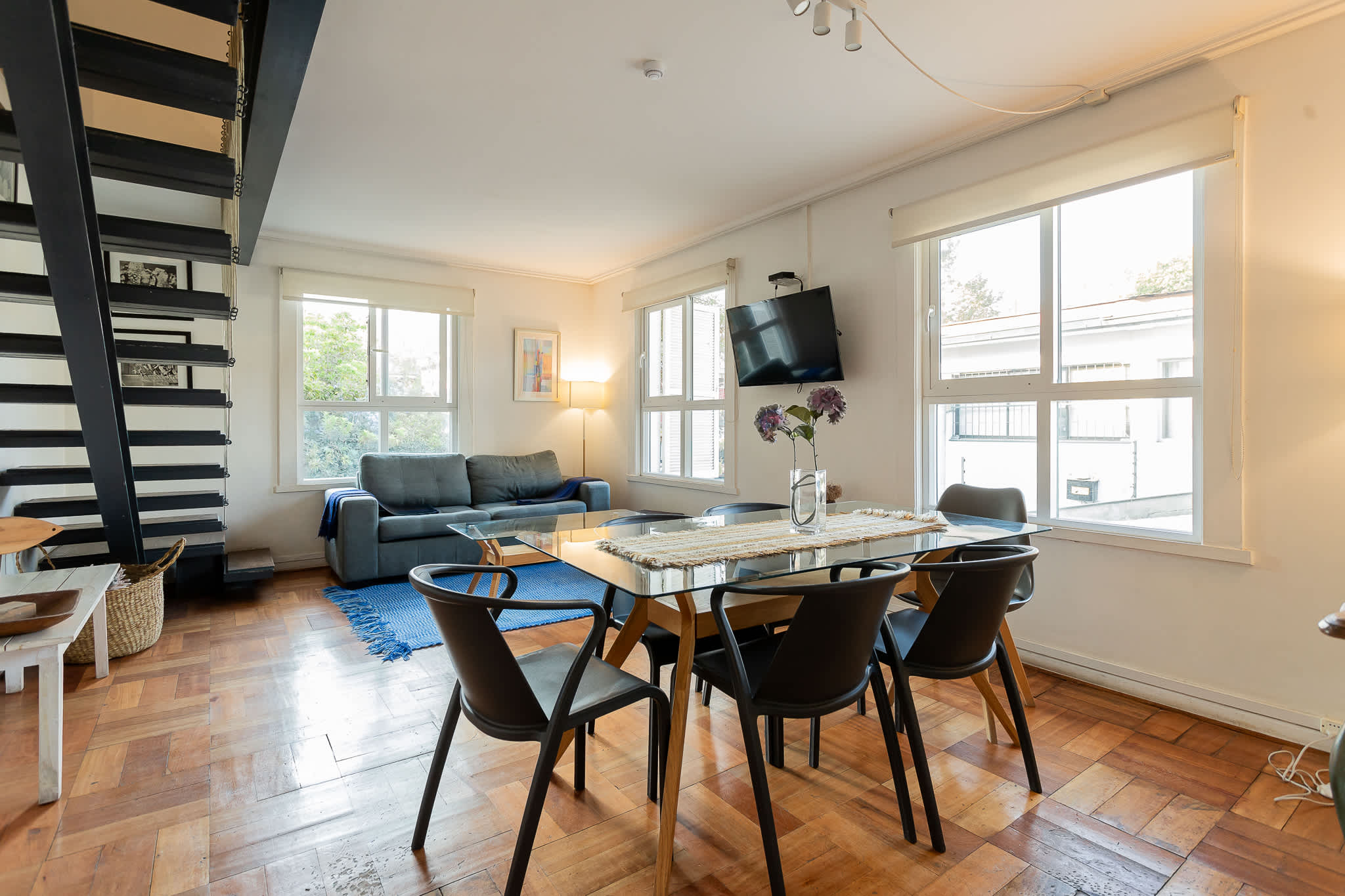 Bright and modern living space with a sleek dining area, cozy sofa, and abundant natural light, perfect for relaxation.