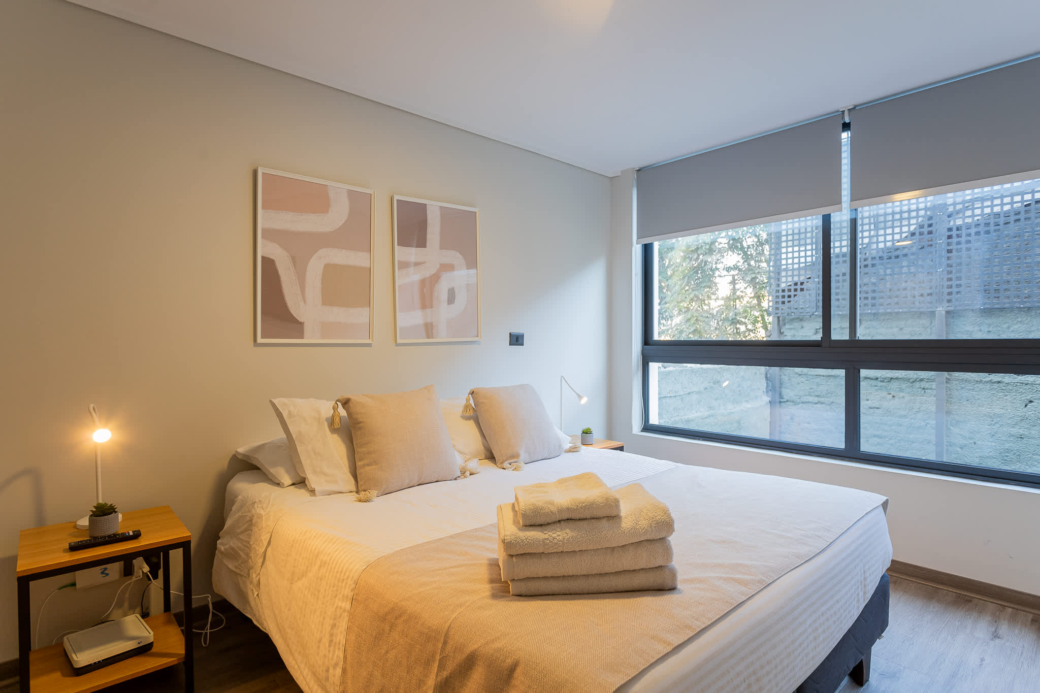 Relax in this cozy bedroom with modern decor and ample natural light, perfect for unwinding after a day exploring the city.