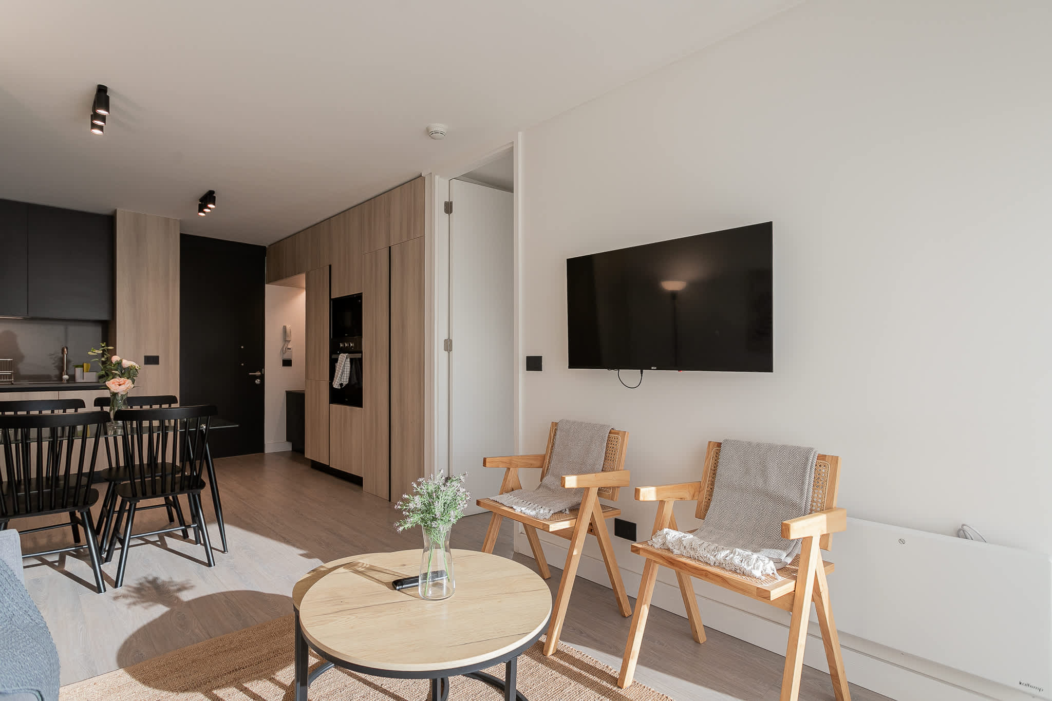 Bright and modern living space with sleek furnishings and a cozy dining area, perfect for relaxing or entertaining.