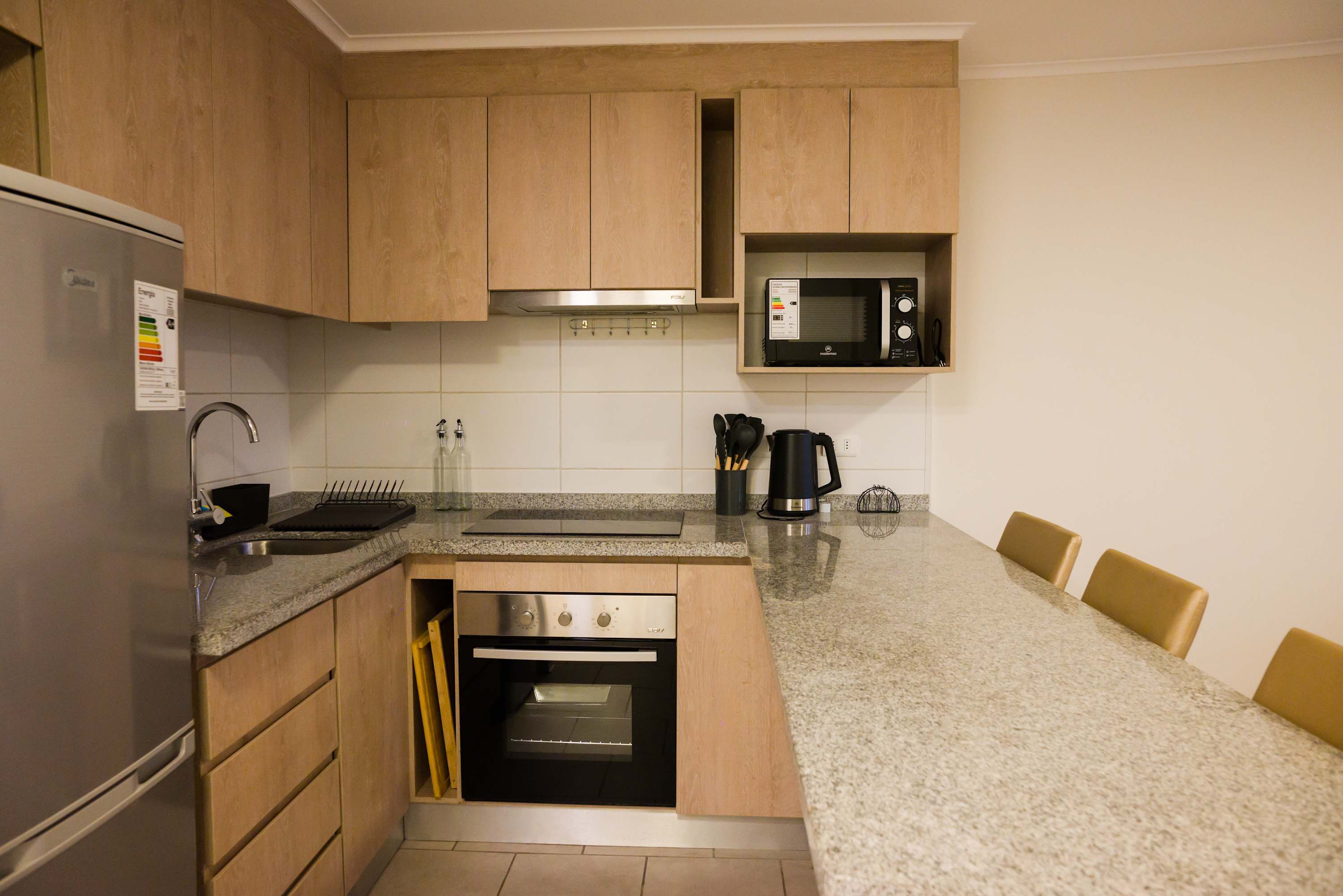 Sleek and modern kitchen with all essentials for a cozy stay, featuring granite countertops and stainless steel appliances.