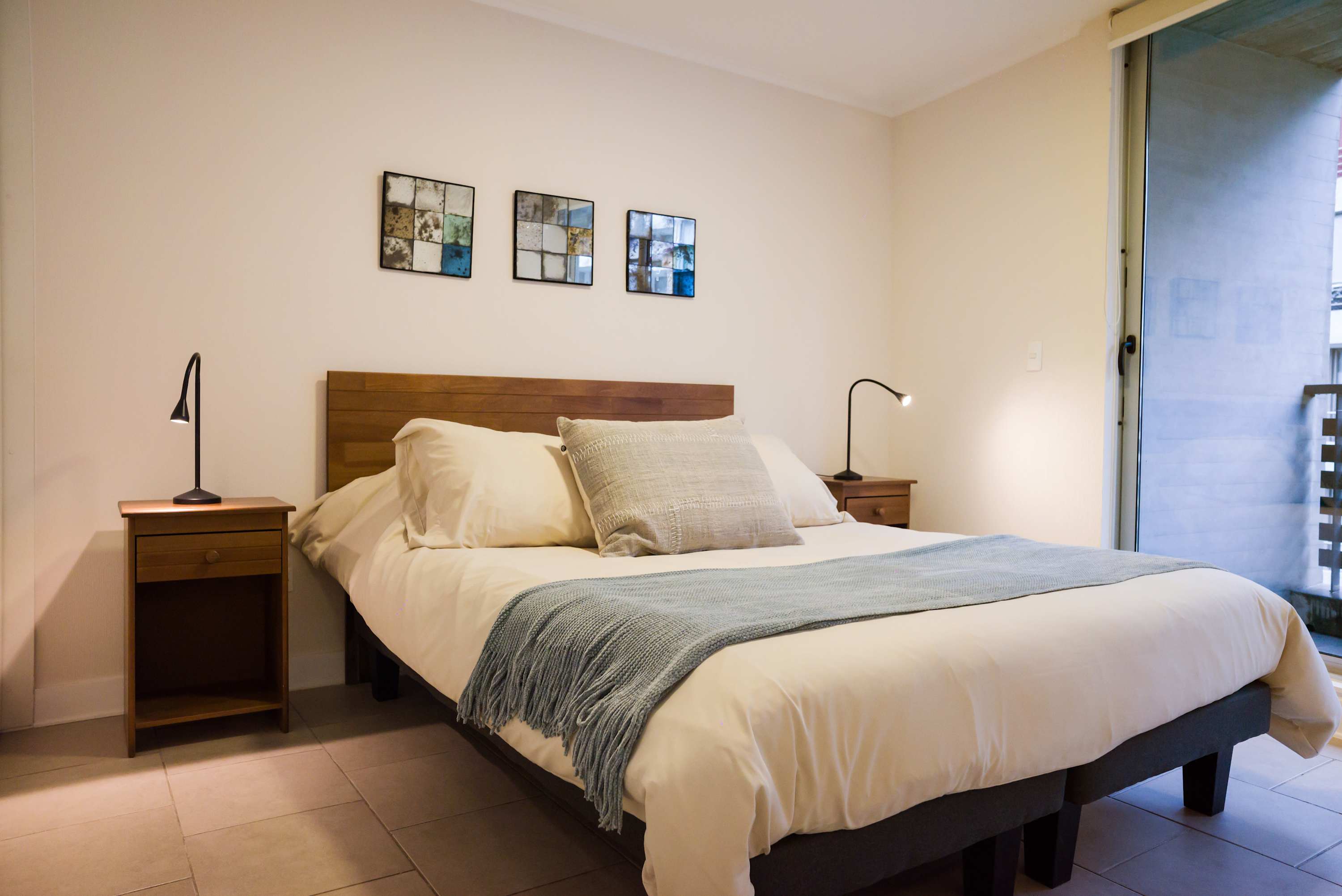 Relax in this serene bedroom with cozy linens and natural light, perfect for a restful stay.