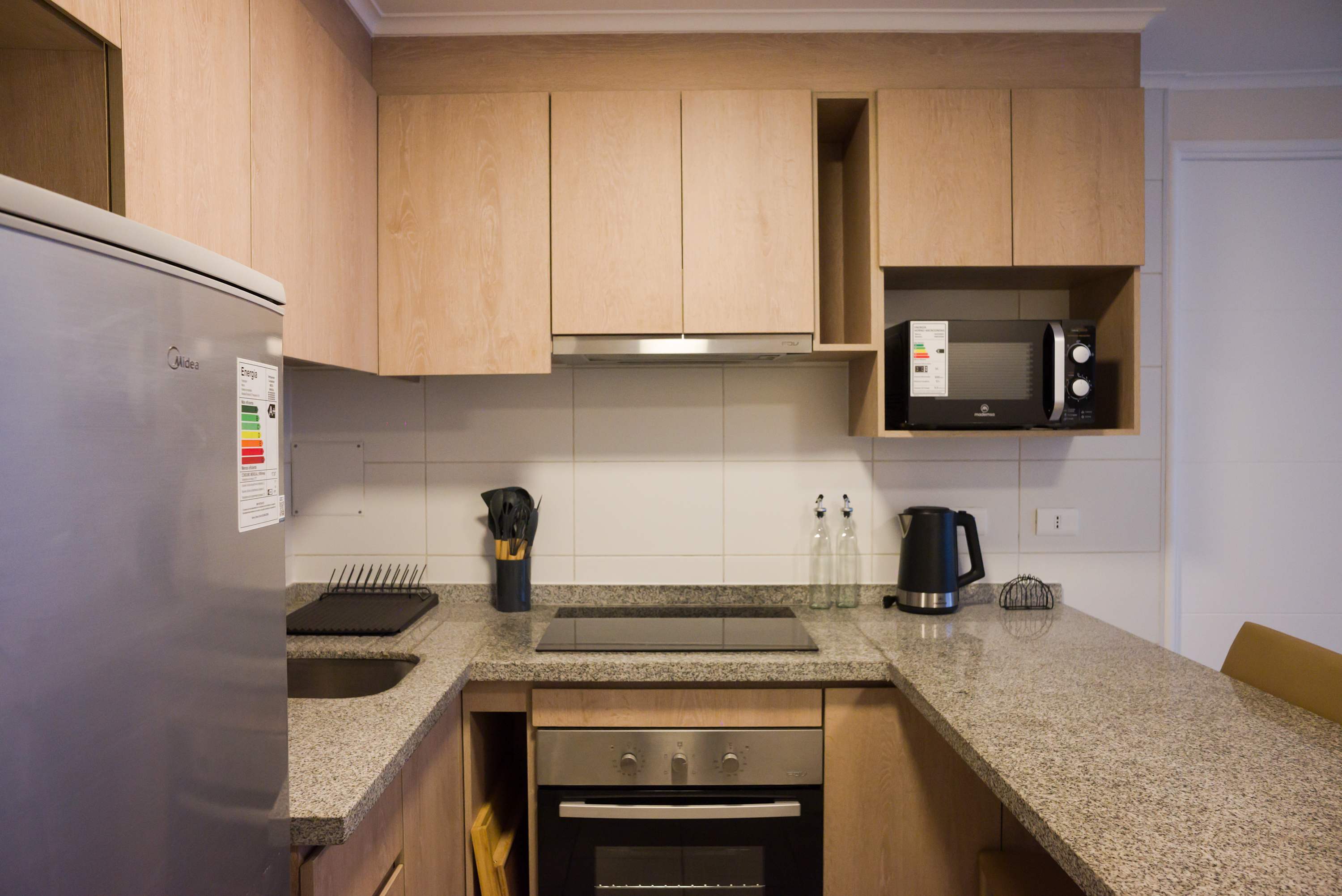 Sleek and modern kitchen with all essentials for a comfortable stay, featuring granite countertops and stainless steel appliances.