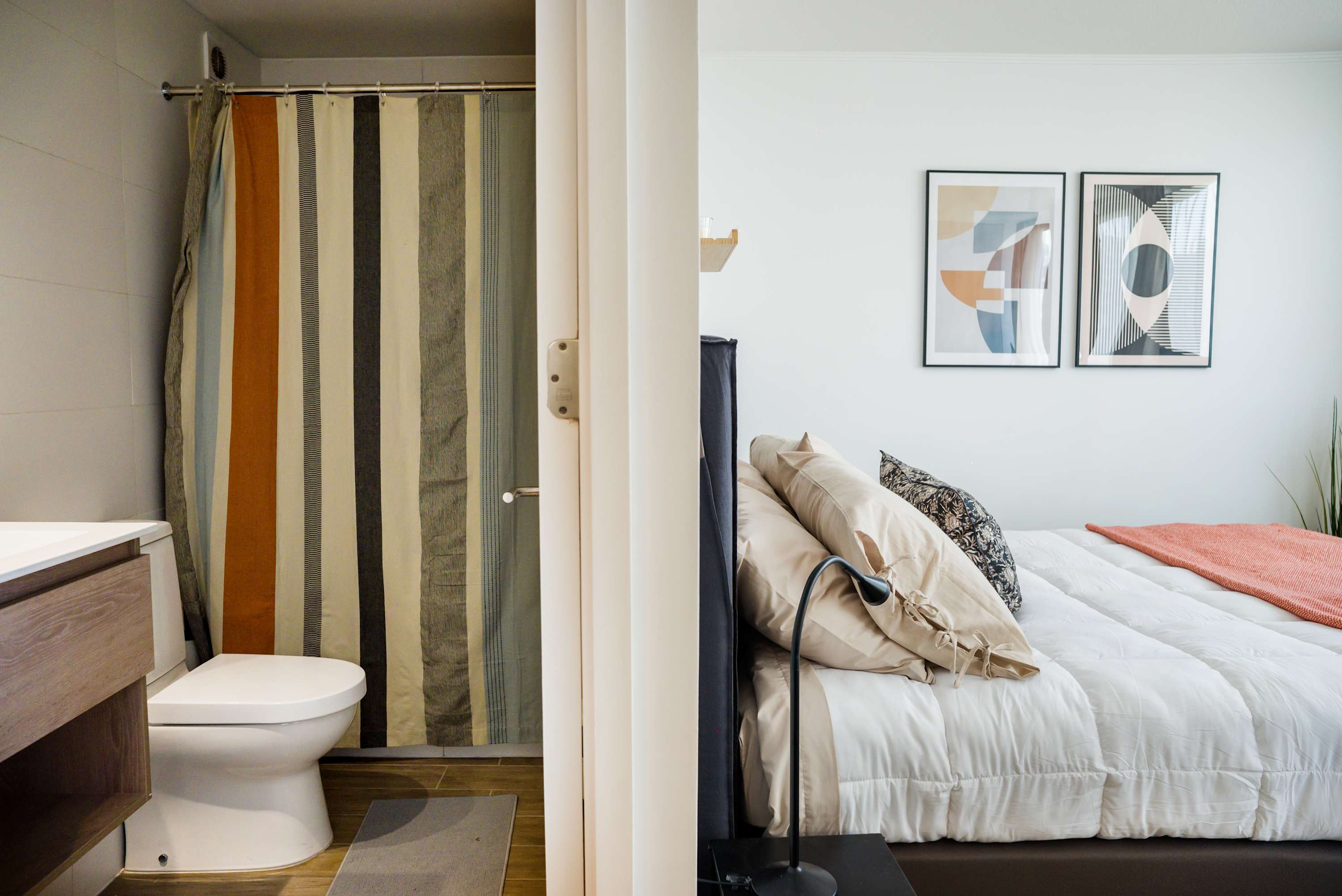 Cozy studio with modern art and vibrant shower curtain, perfect for a relaxing stay.