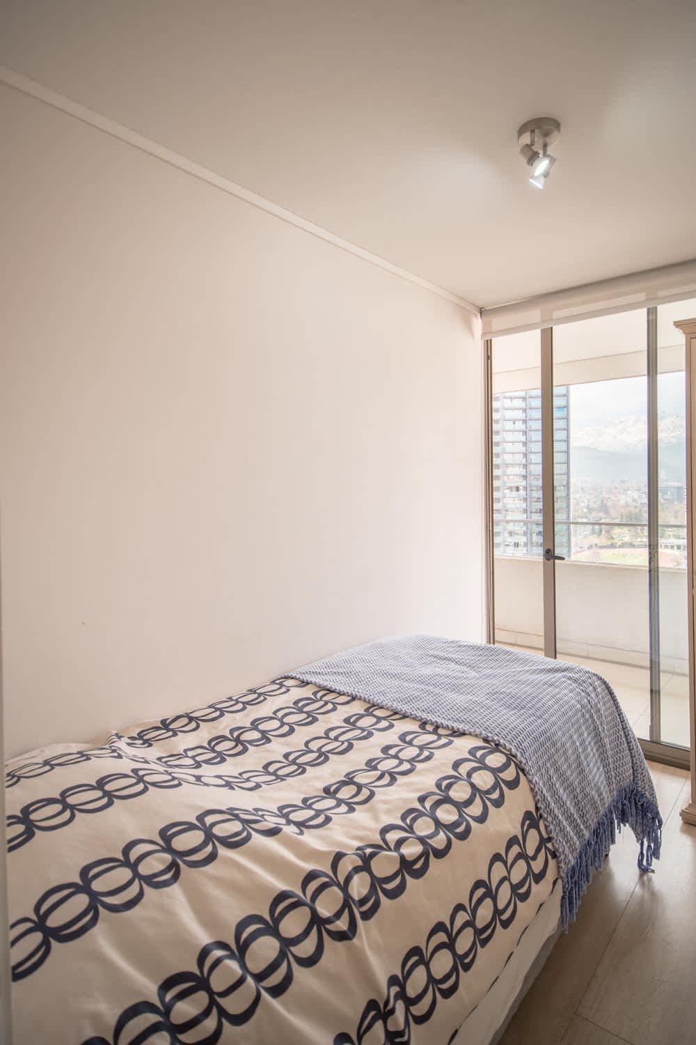Cozy bedroom with balcony access offering stunning city and mountain views, perfect for a relaxing stay.