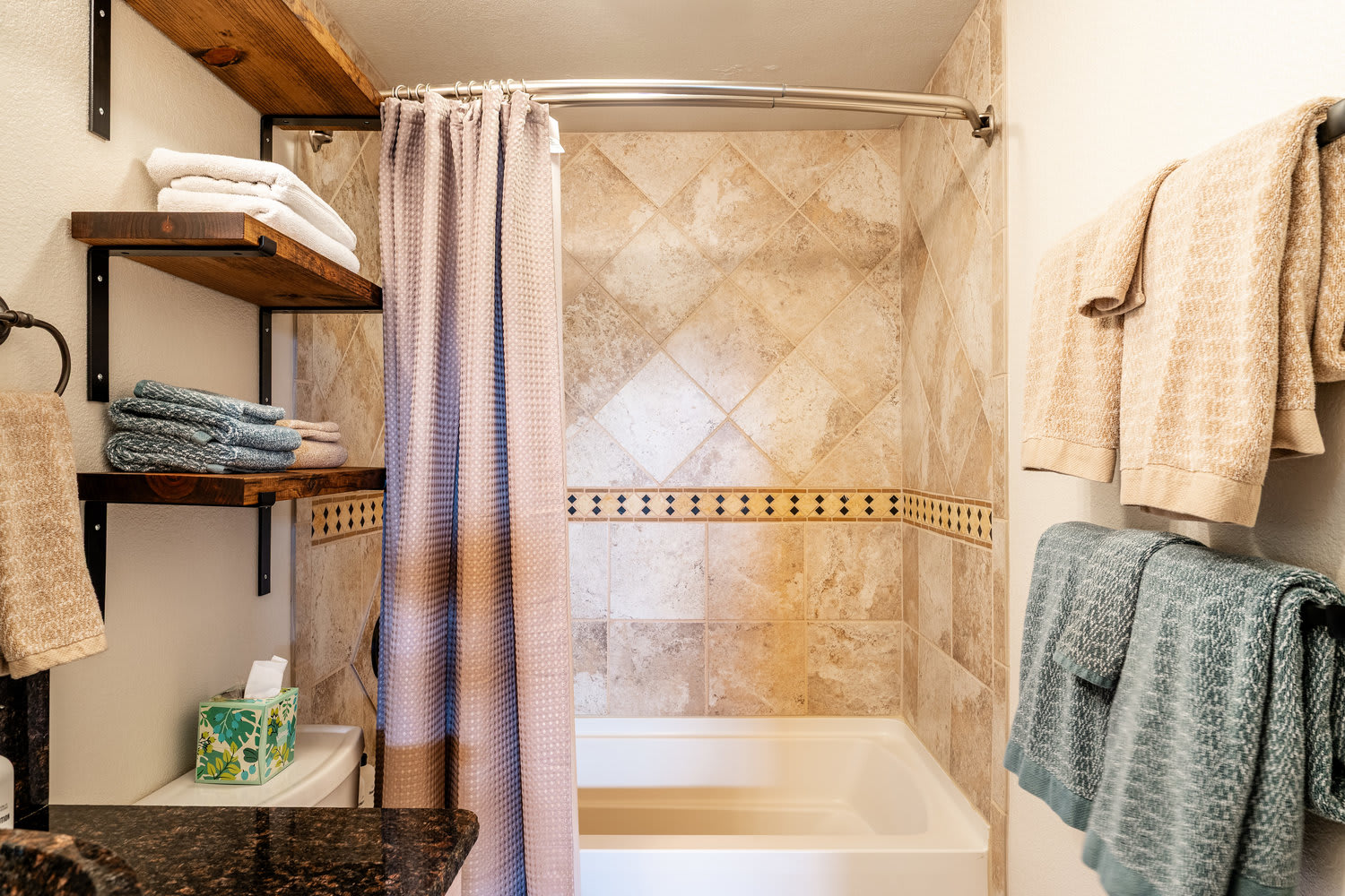 Travertine-tile bathroom at The Maple with a soaking tub-and-shower combo — Sheridan, Wyoming