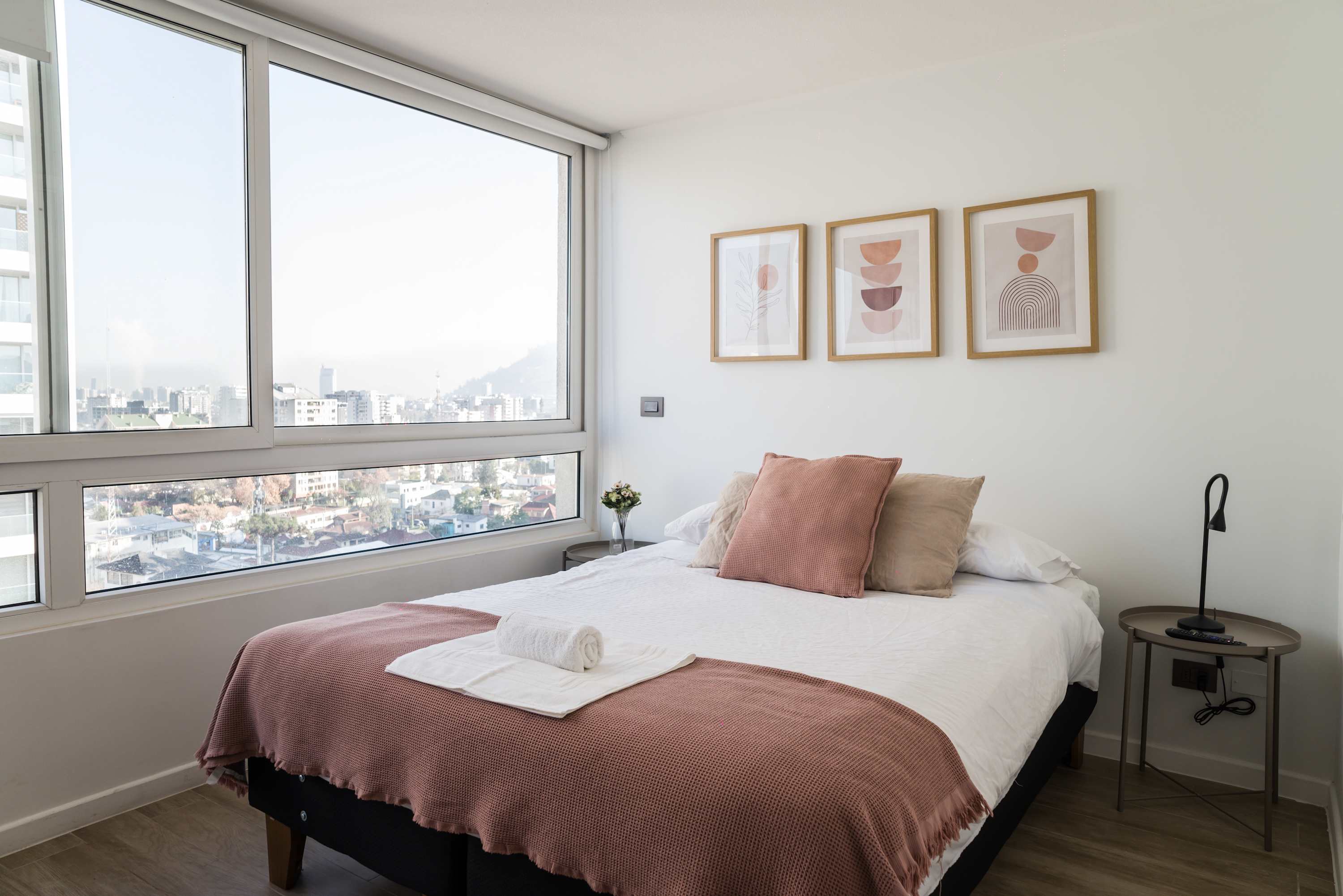 Enjoy breathtaking city views from this chic, sunlit bedroom, perfect for a cozy retreat in the heart of the city.