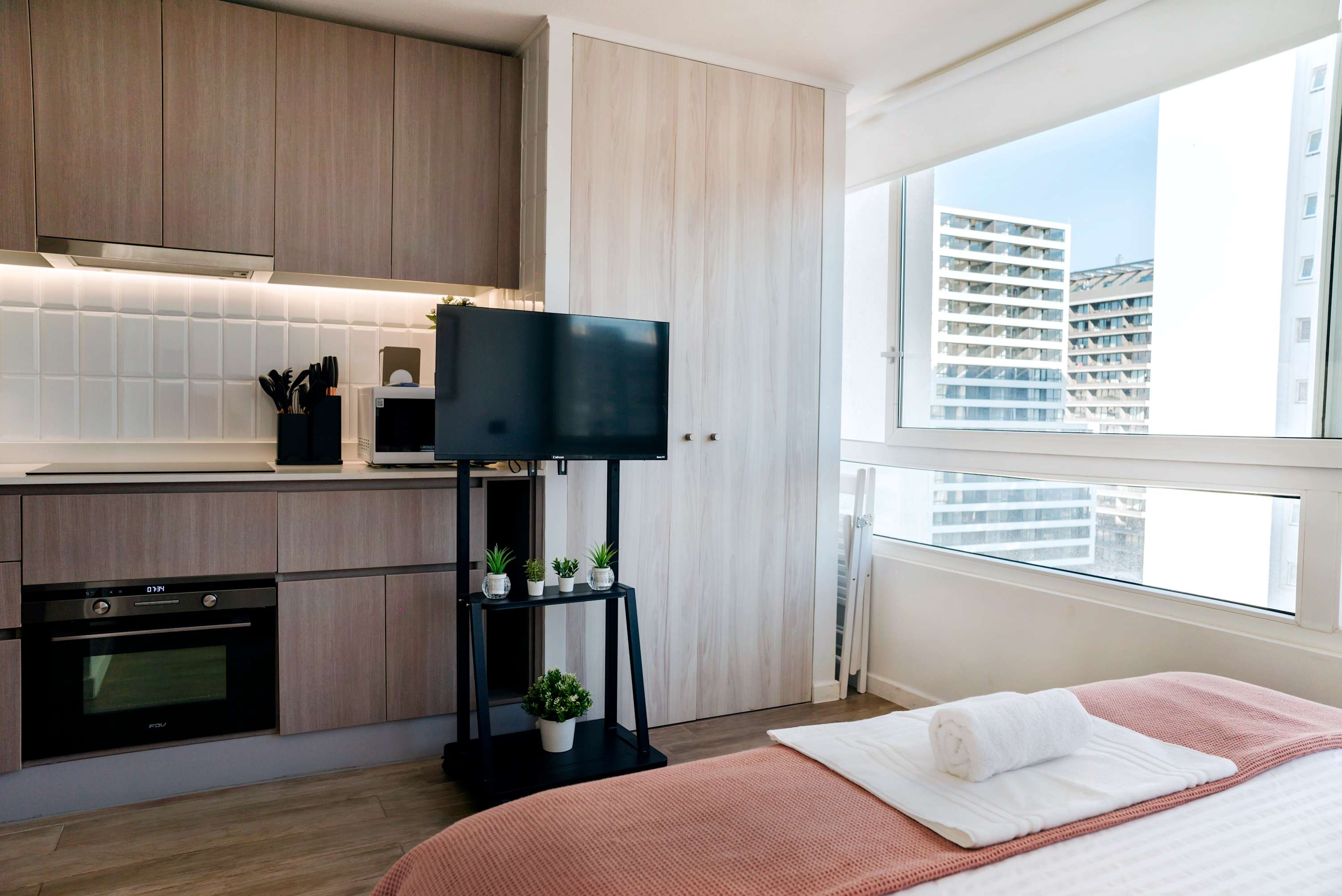 Enjoy city views from this modern studio kitchen, complete with sleek appliances and cozy decor.