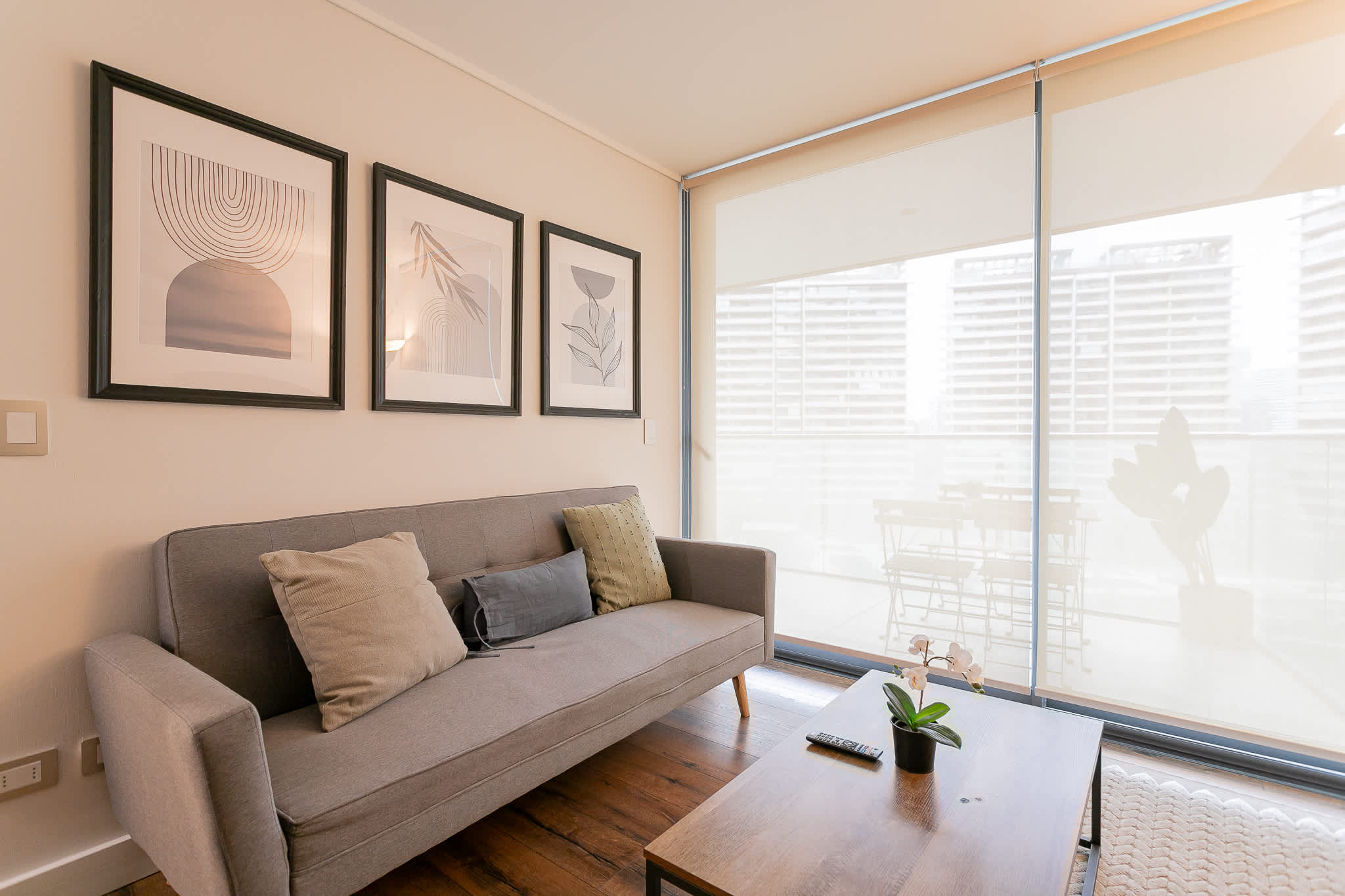 Relax in this stylish living room with a cozy sofa, chic decor, and a sunlit balcony view—perfect for unwinding after exploring the city.