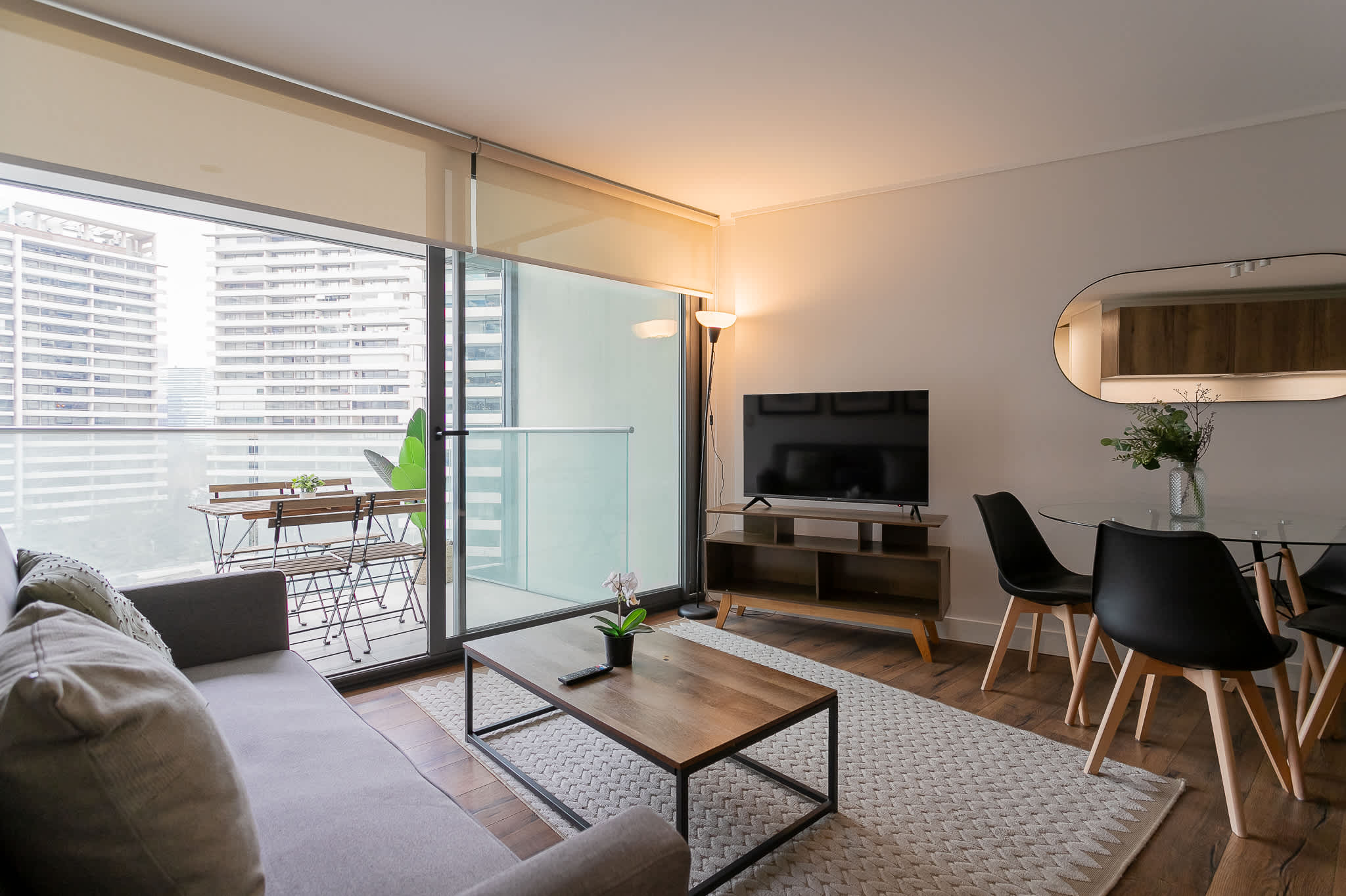 Relax in this stylish living room with a cozy sofa, modern dining area, and a private balcony offering city views.