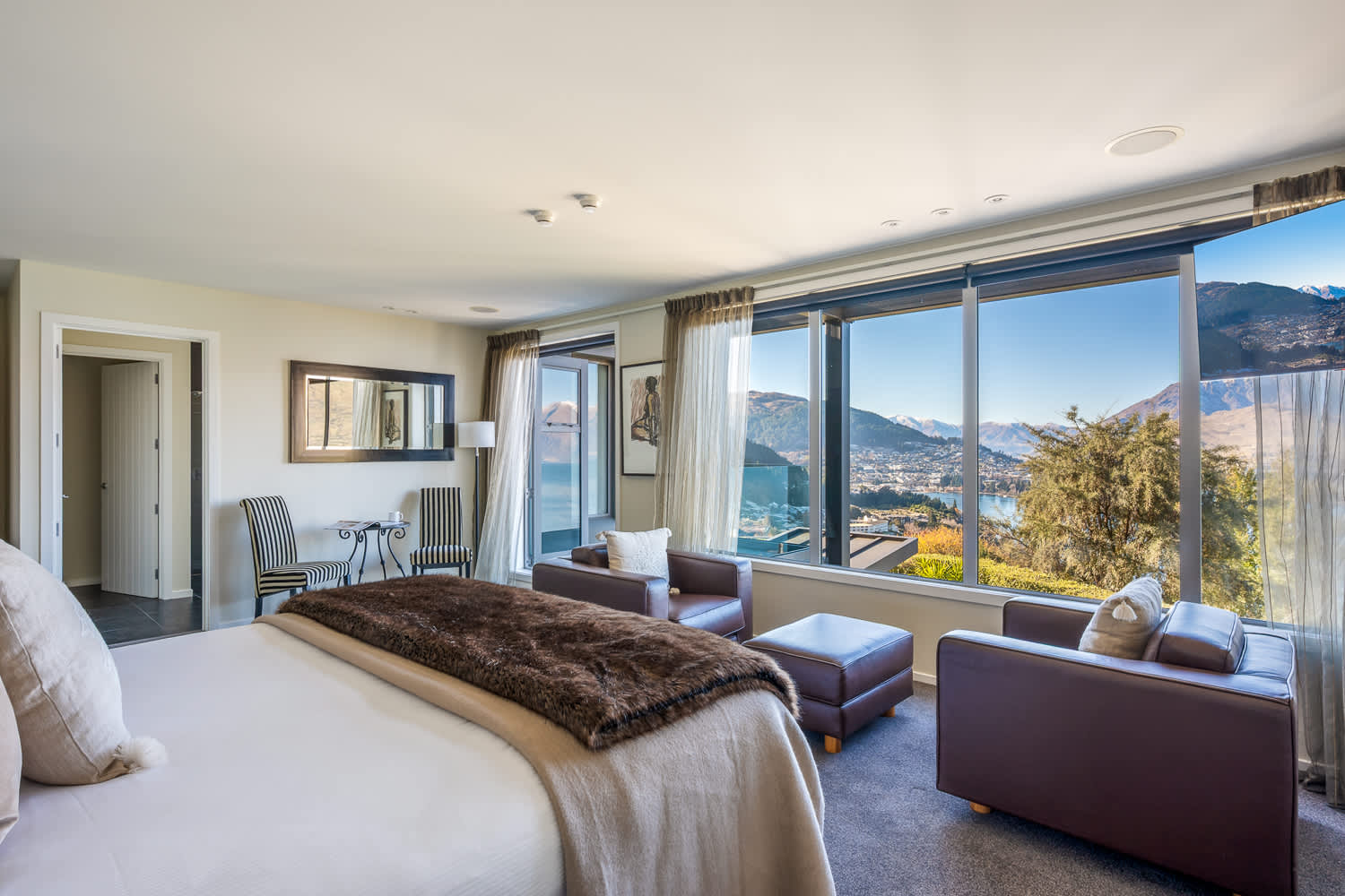 The spacious master bedroom features a luxurious king-size bed and large windows showcasing stunning lake and mountain views. Enjoy the privacy and convenience of your own modern ensuite bathroom.
