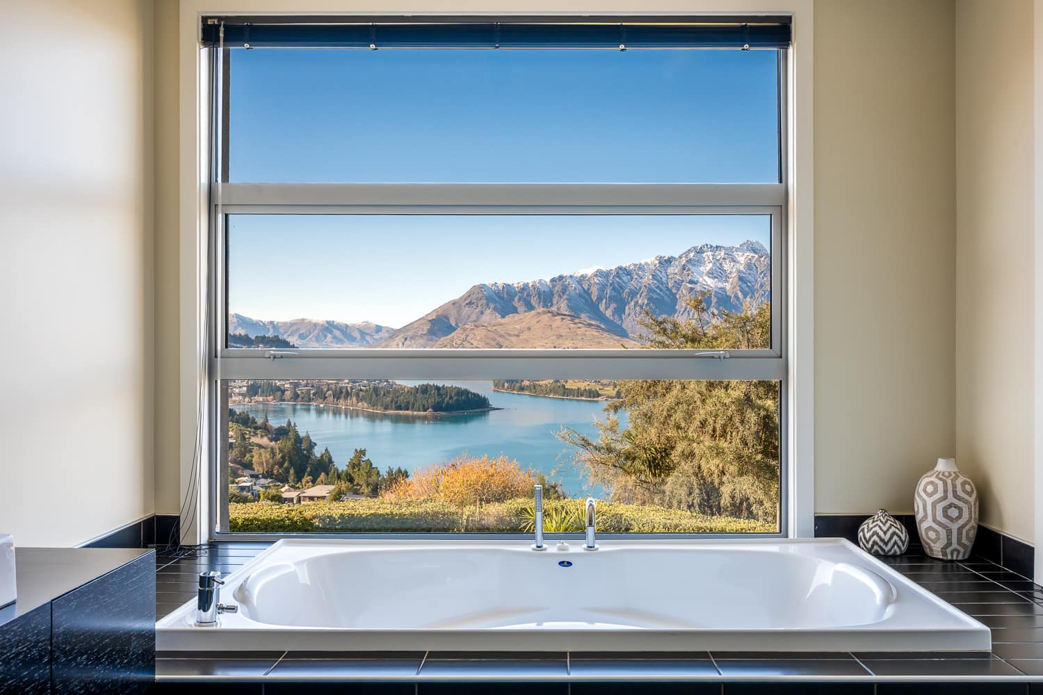 The master ensuite boasts a sleek, modern design with large windows framing stunning lake and mountain views. Enjoy a soak in the bath while taking in Queenstown’s breathtaking scenery.