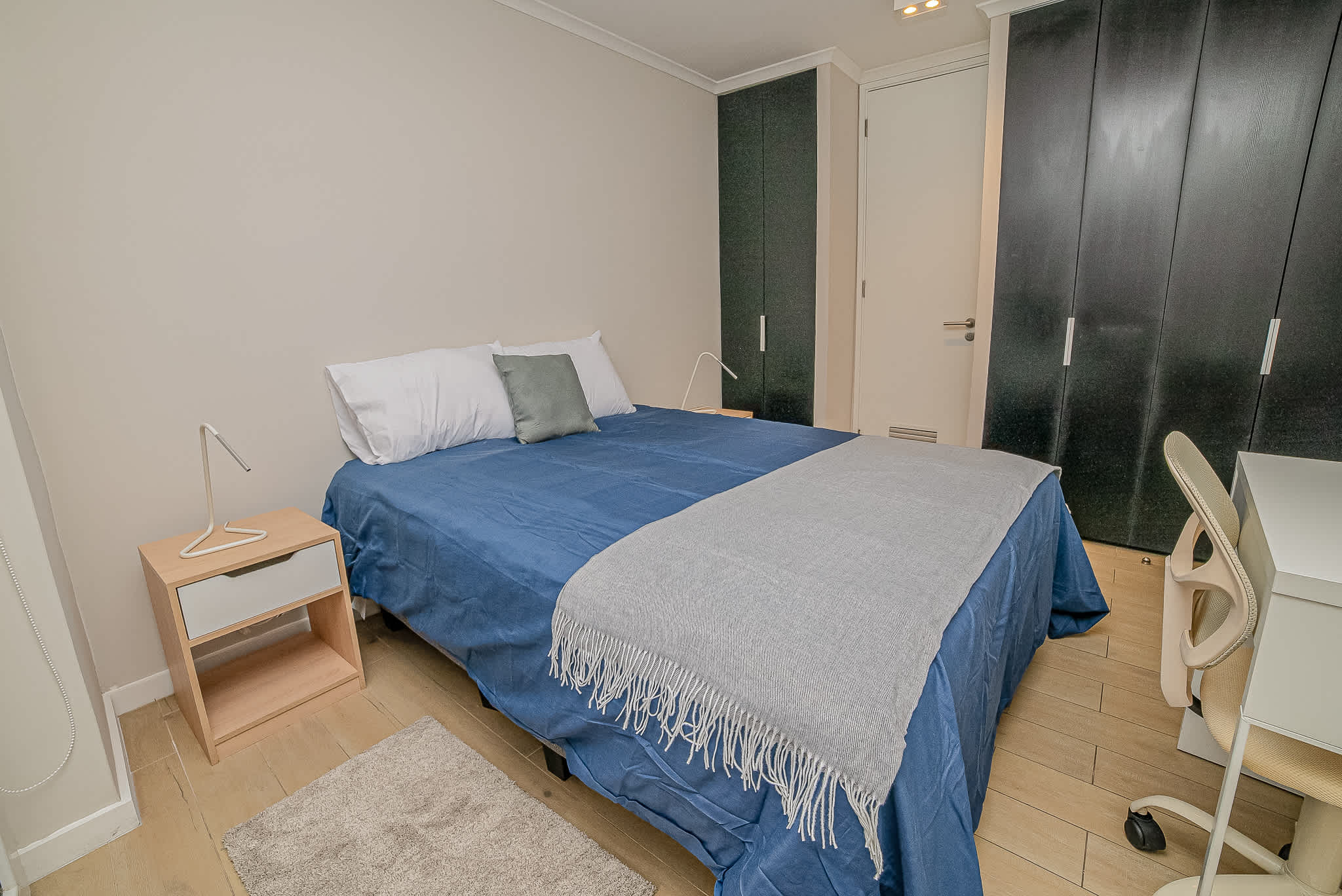 Cozy bedroom with ample storage and a comfortable workspace, perfect for relaxation and productivity.