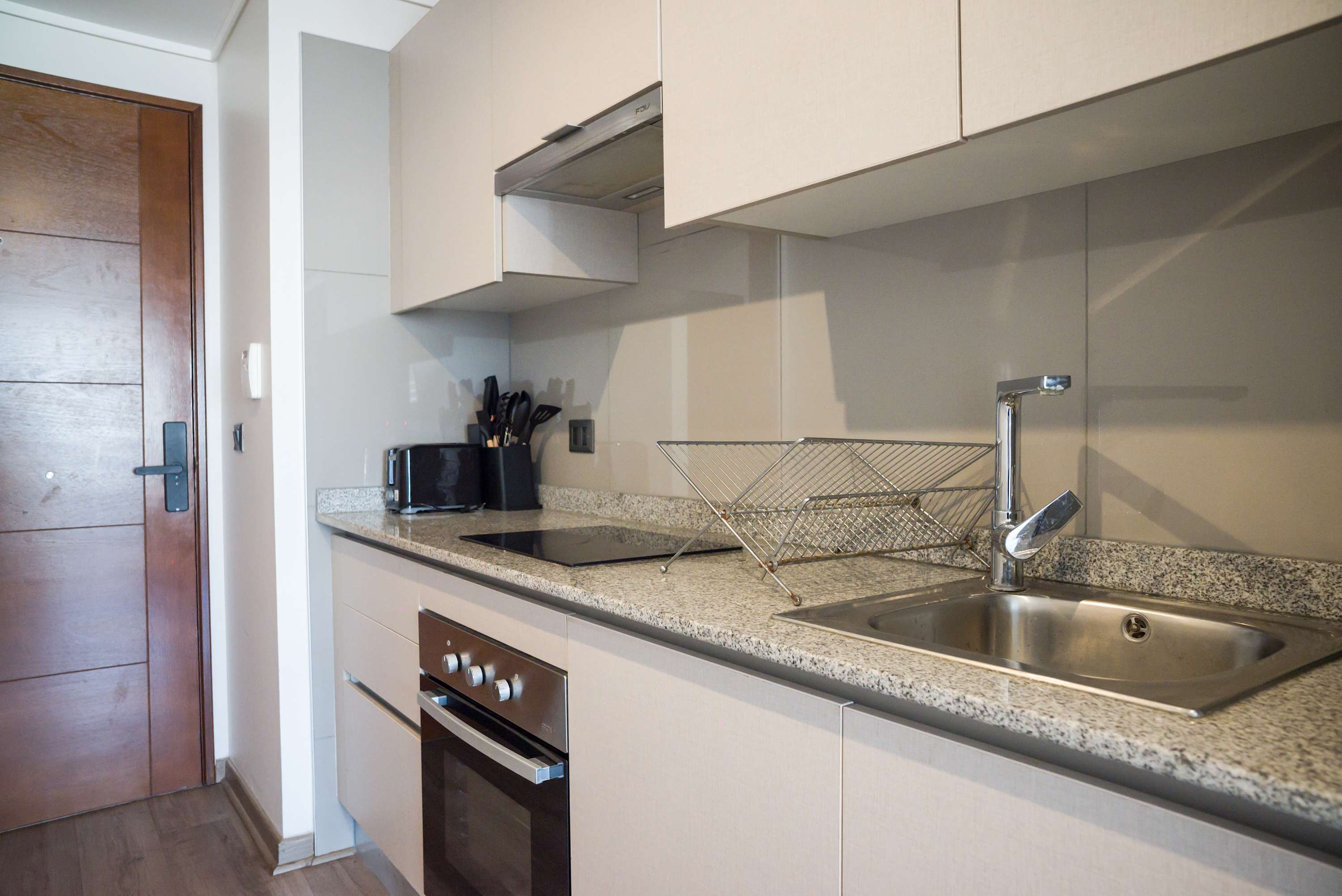 Modern studio kitchen with sleek appliances and granite countertops, perfect for cozy meals in a compact space.